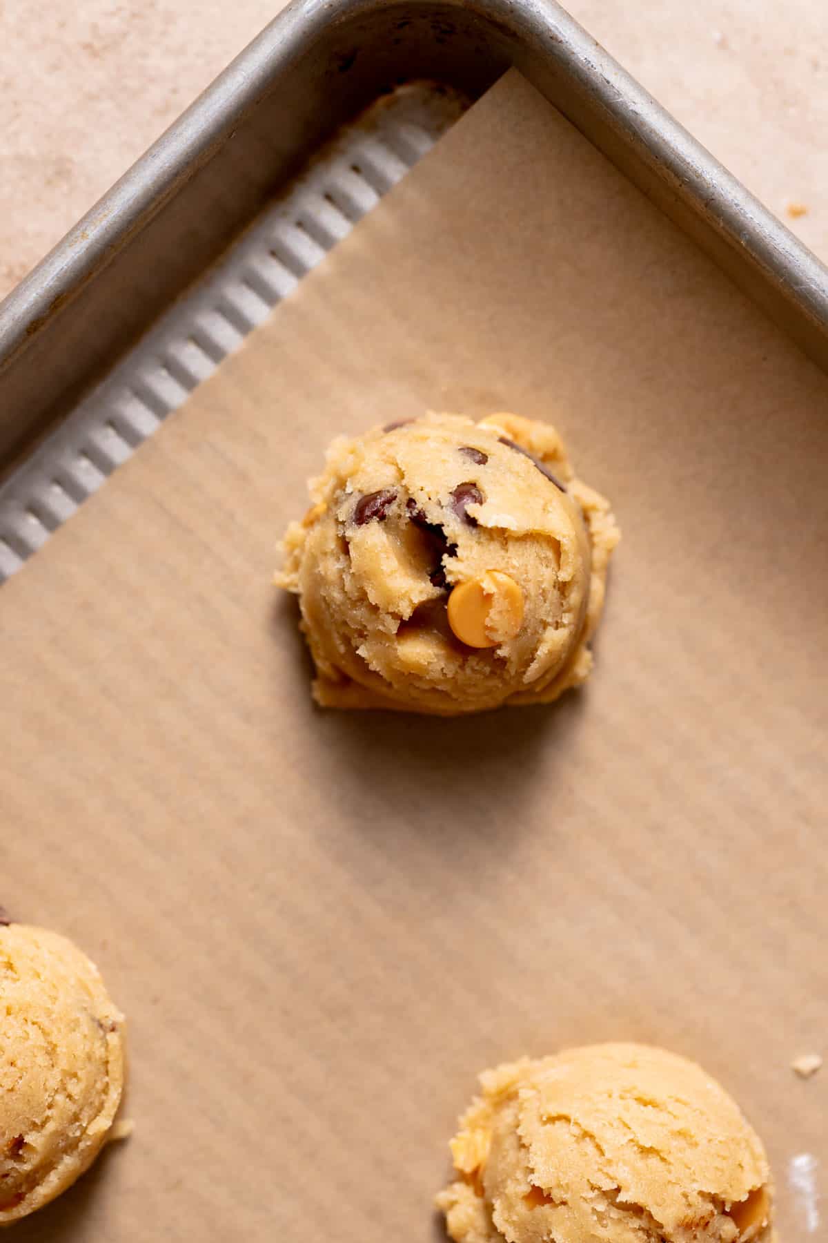 butterscotch chocolate chip cookie dough ball on a baking sheet.