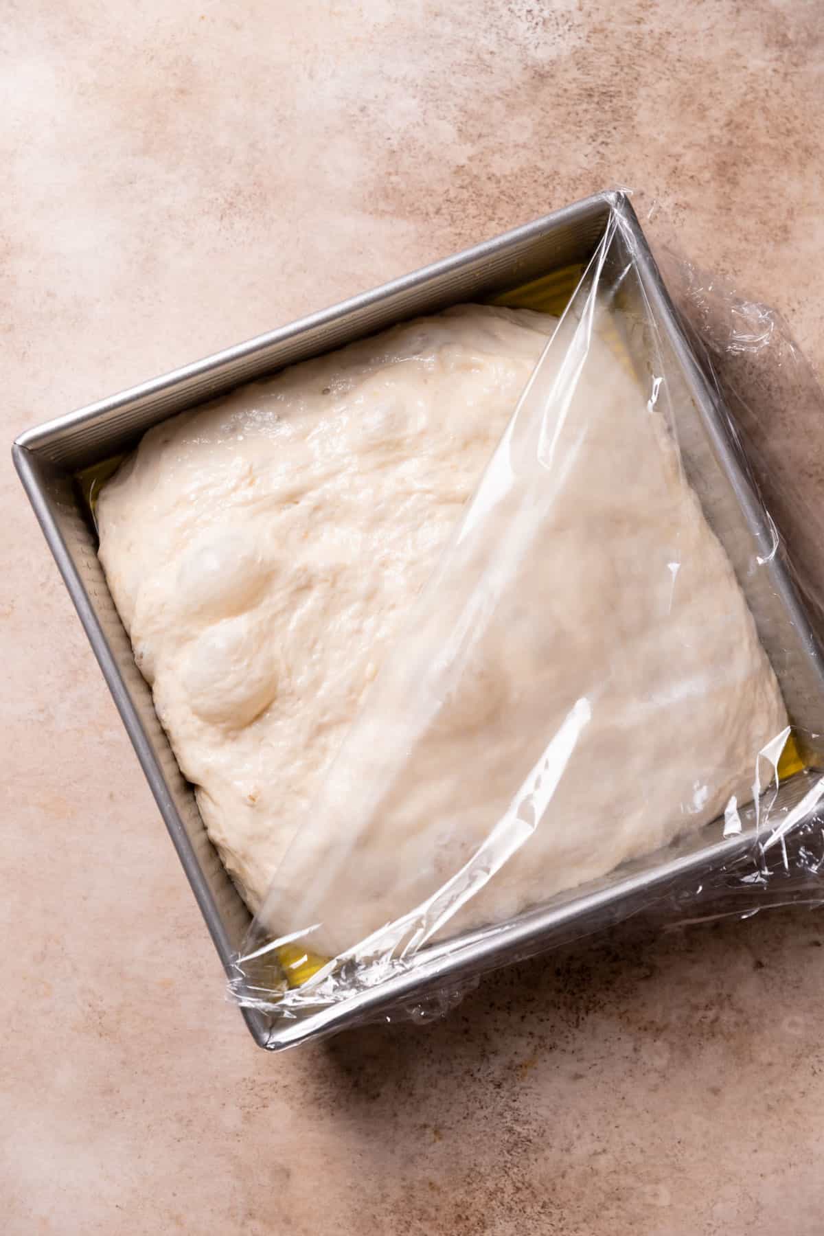 the bubbly focaccia dough in a baking pan after the second rise.