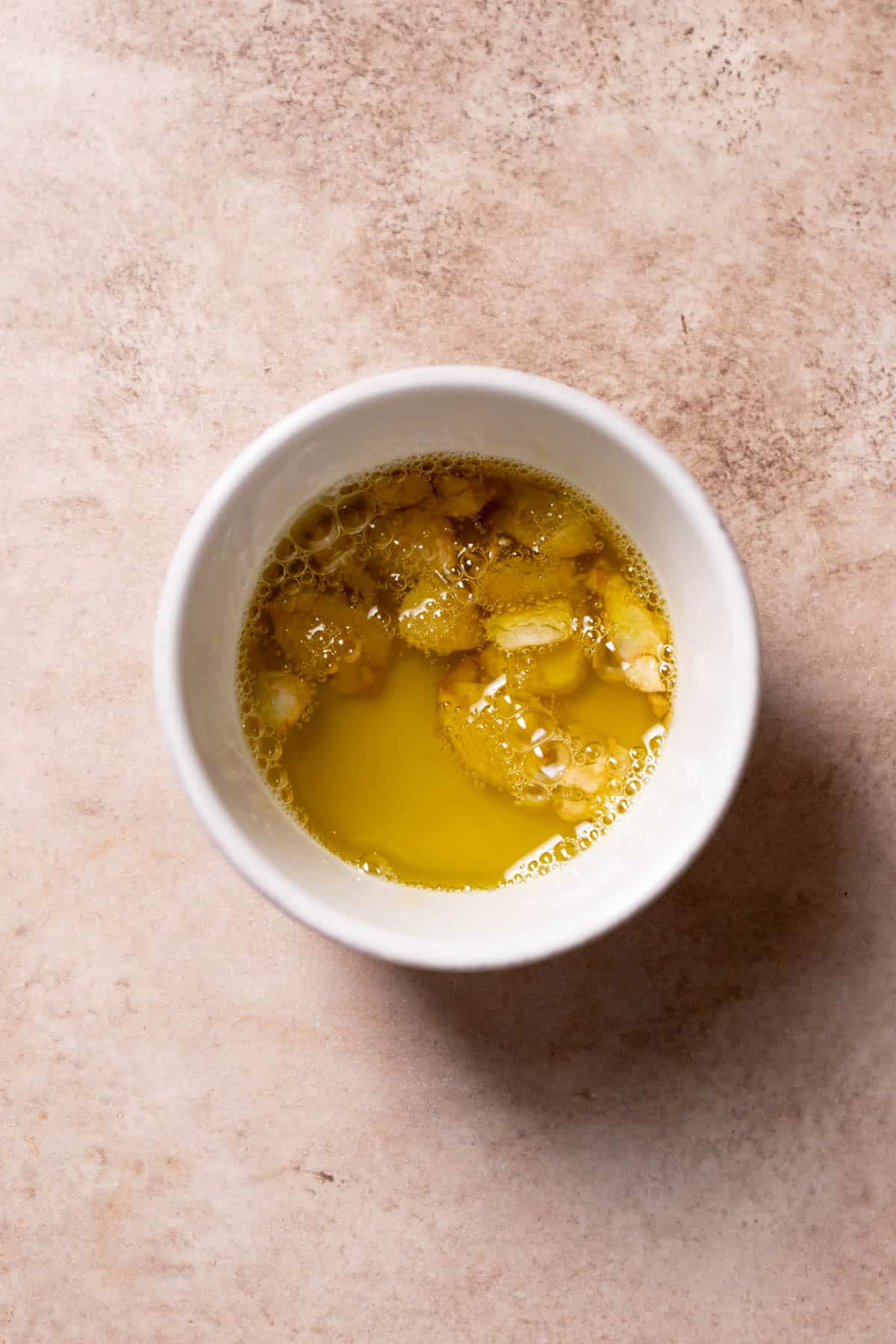 garlic cloves and olive oil in a white bowl.