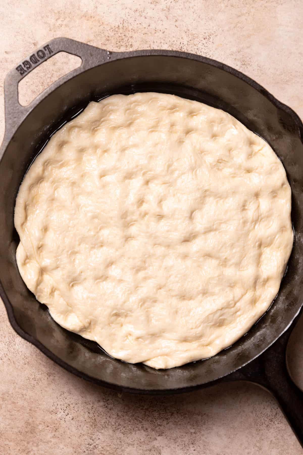 pizza dough on the bottom of a cast iron pan.