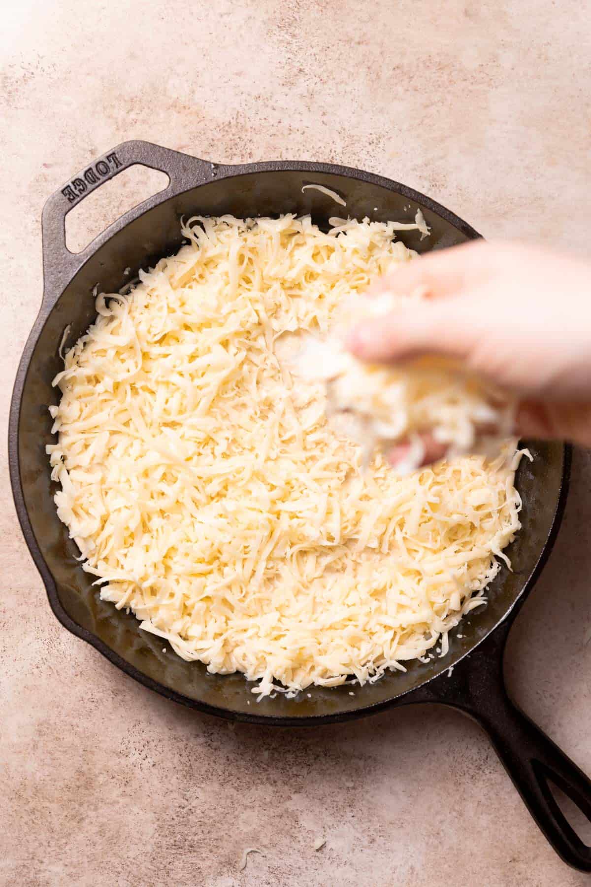 sprinkling mozzarella cheese over the pizza dough in a pan.