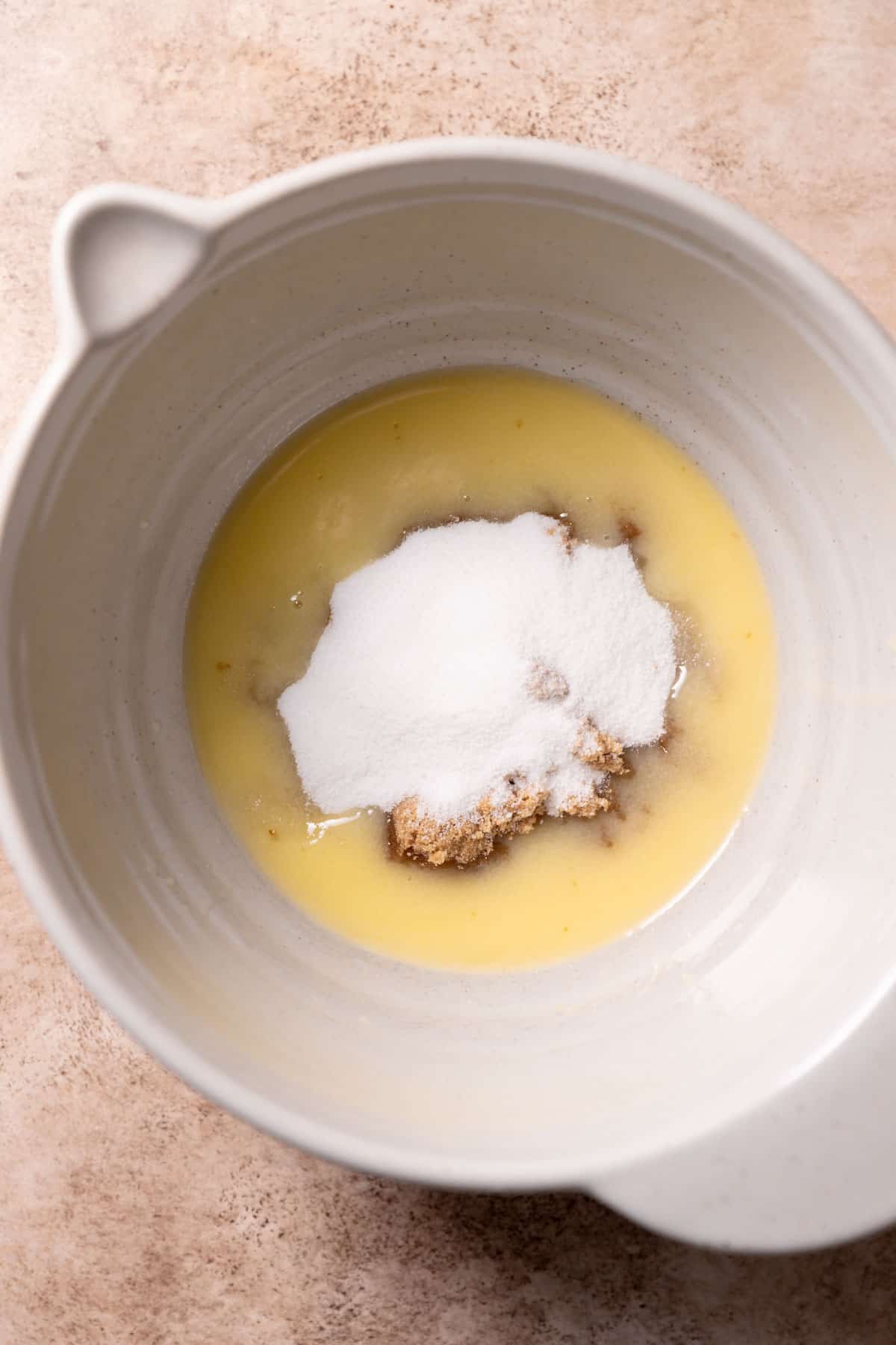 a mixing bowl with melted butter, white sugar, and brown sugar before mixing.