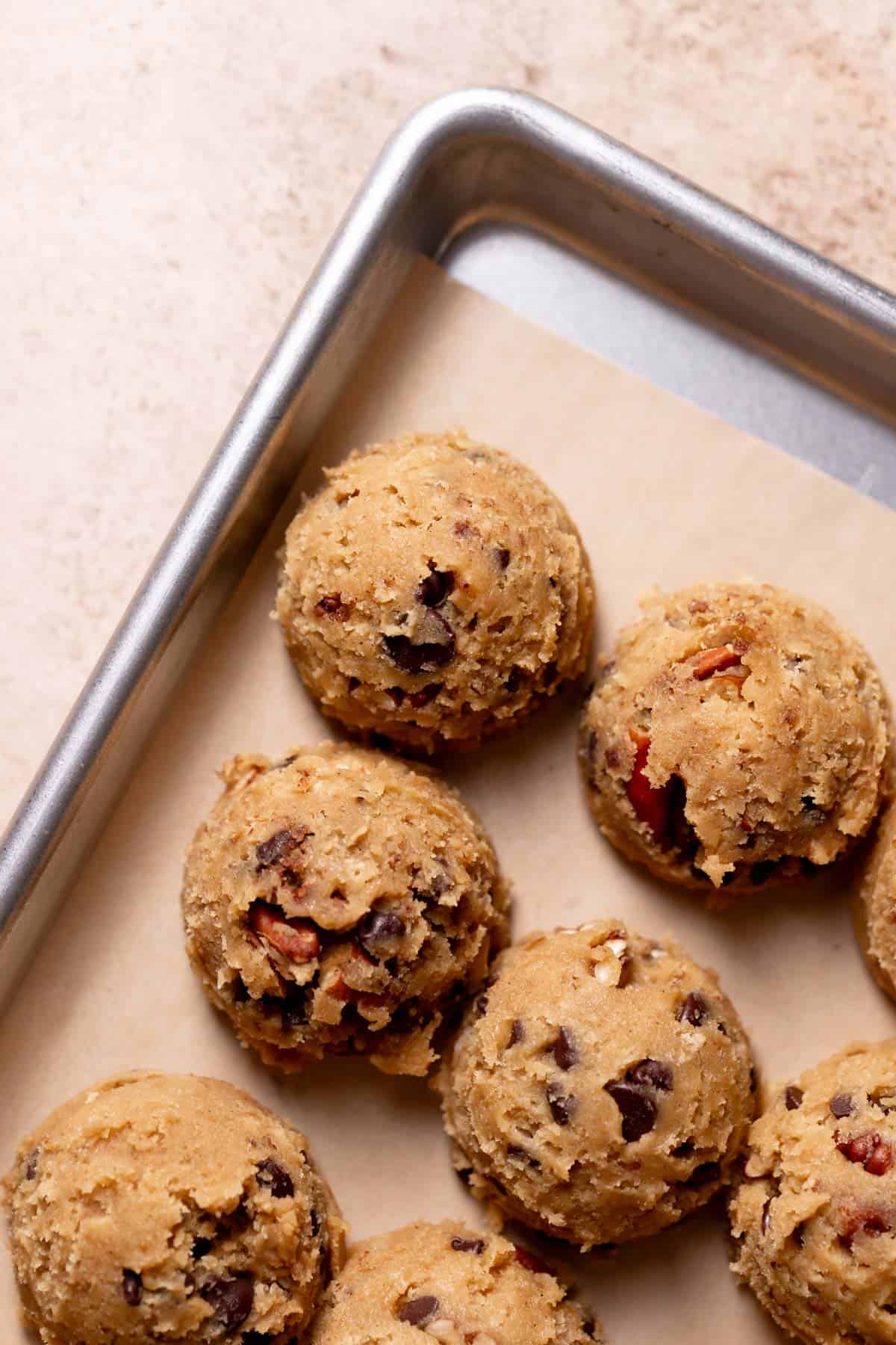 a baking tray with the chocolate pecan cookie dough balls on it.