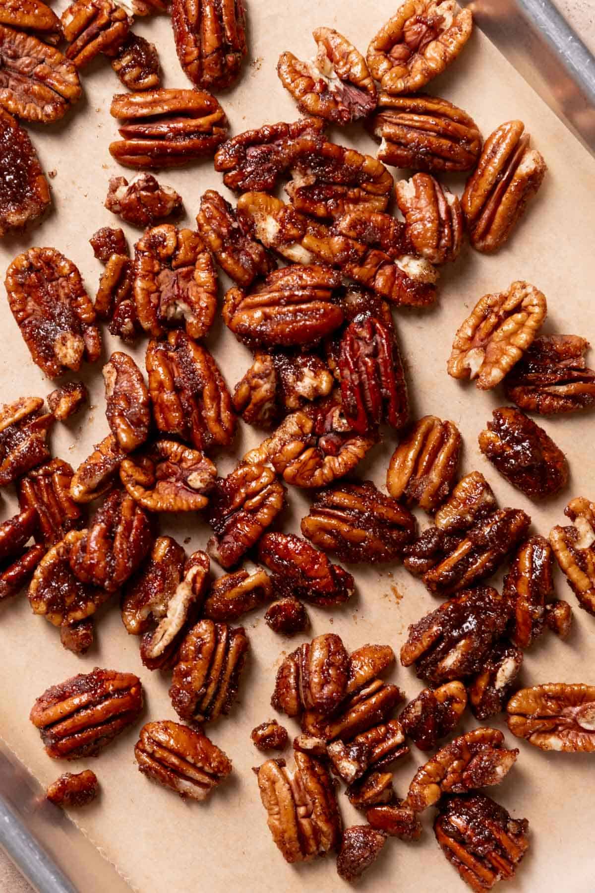 pecans tossed in butter, sugar, and cinnamon on a baking tray.