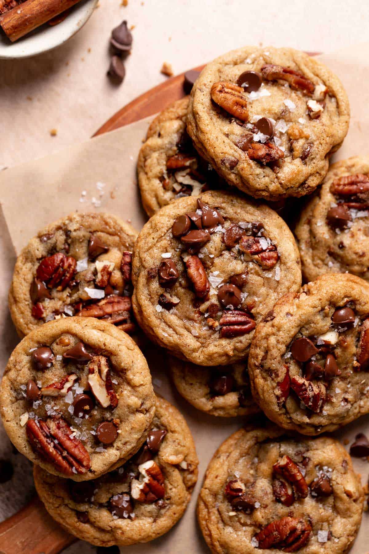 a pile of chocolate chip pecan cookies topped with flaky sea salt and melted chocolate chips.