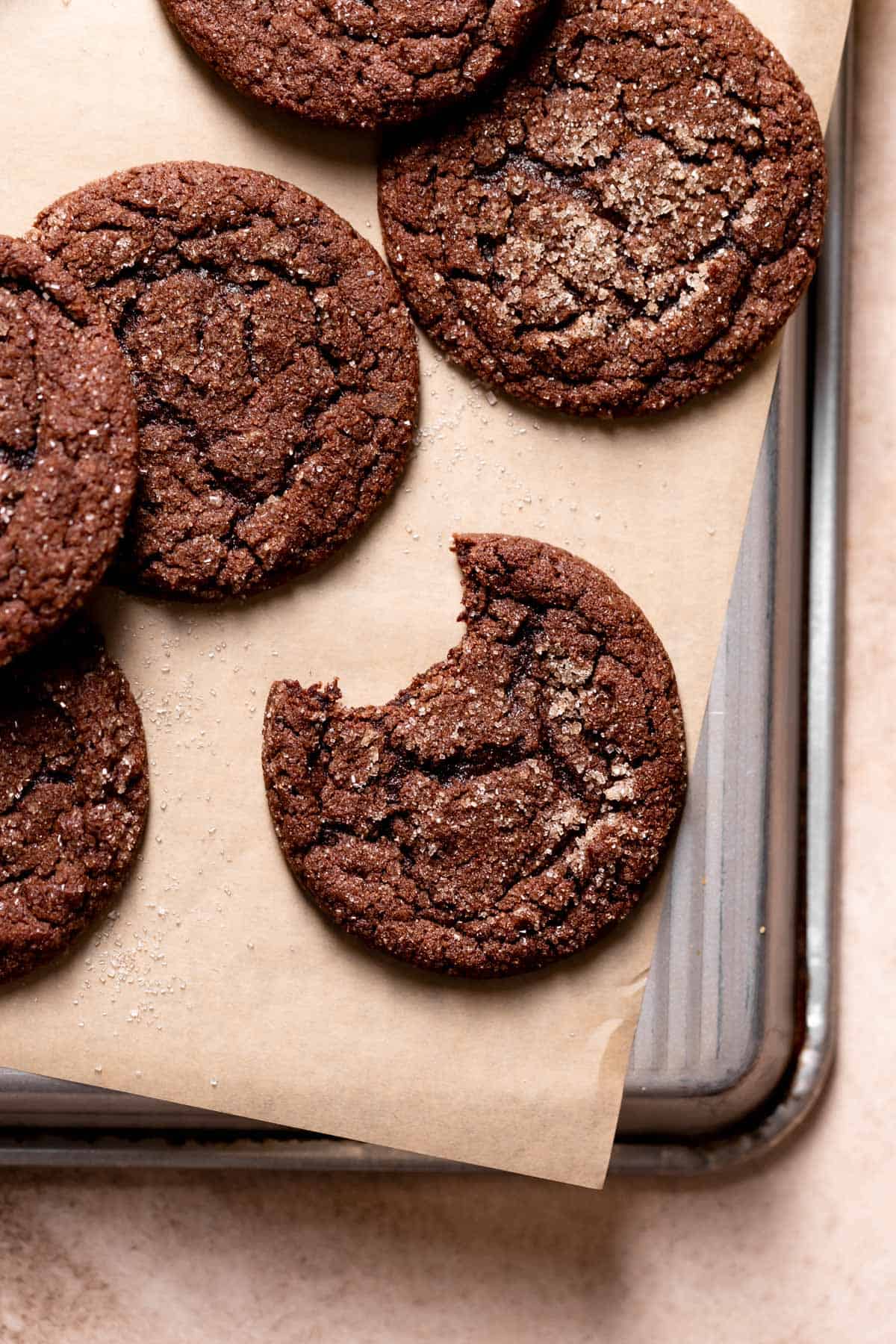 chocolate snickerdoodles with a bite taken out of it on a tray.