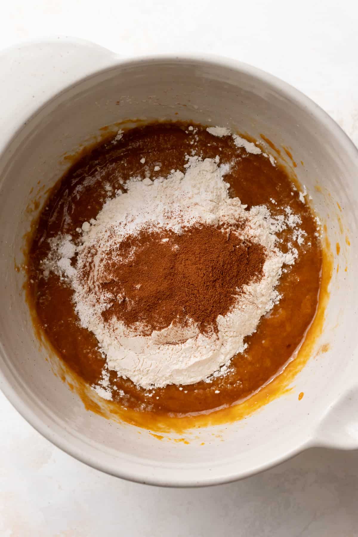 a bowl of pumpkin batter with the dry ingredients on top before mixing.