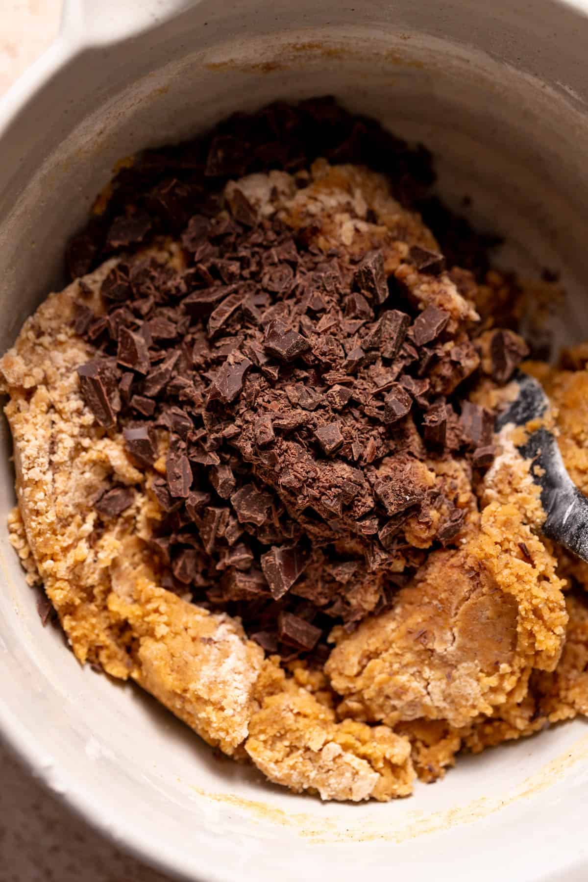 A mixing bowl of the pumpkin cookie dough with the chocolate chips on top before mixing.