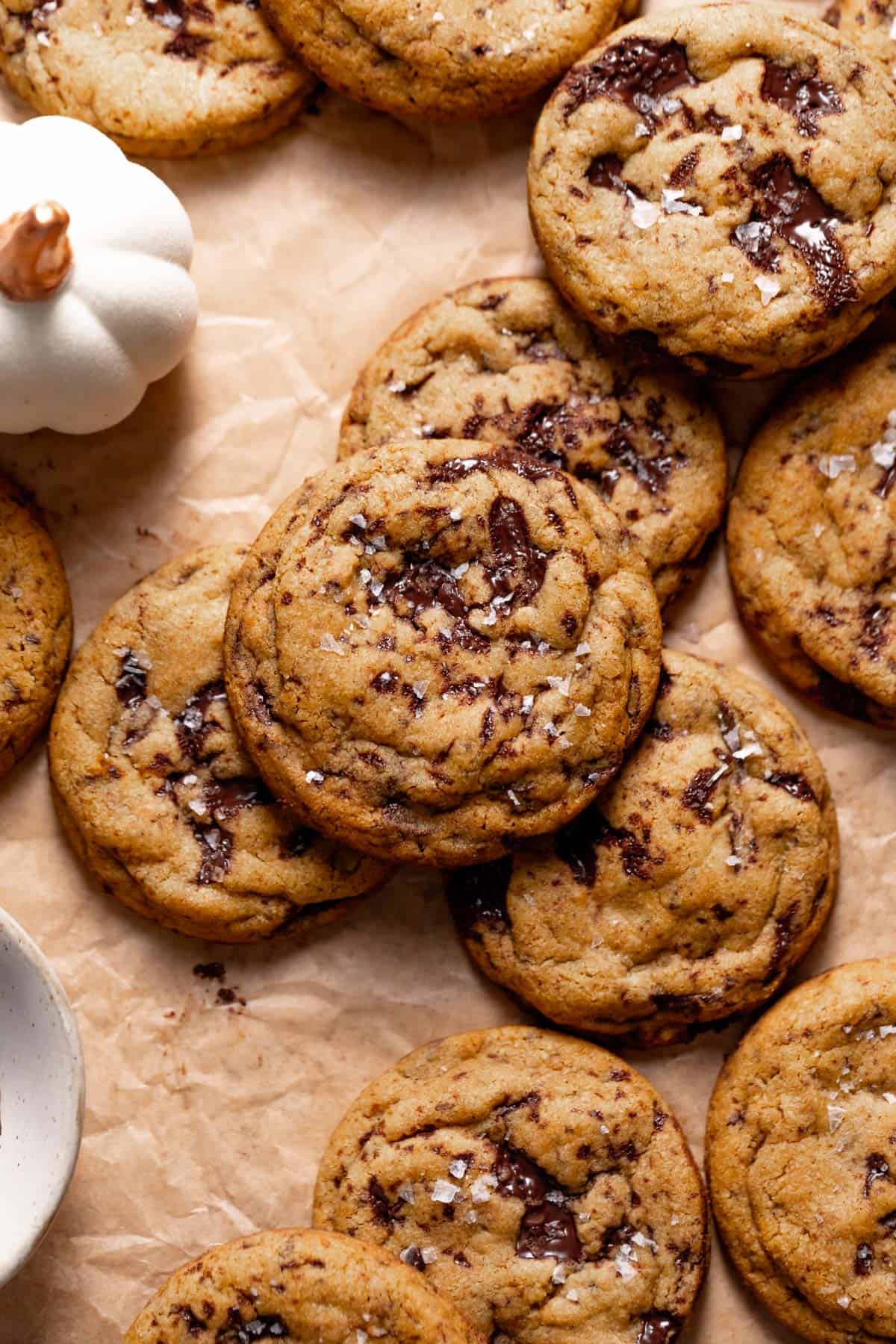 Pumpkin chocolate chip cookies with pools of melty chocolate on parchment paper.