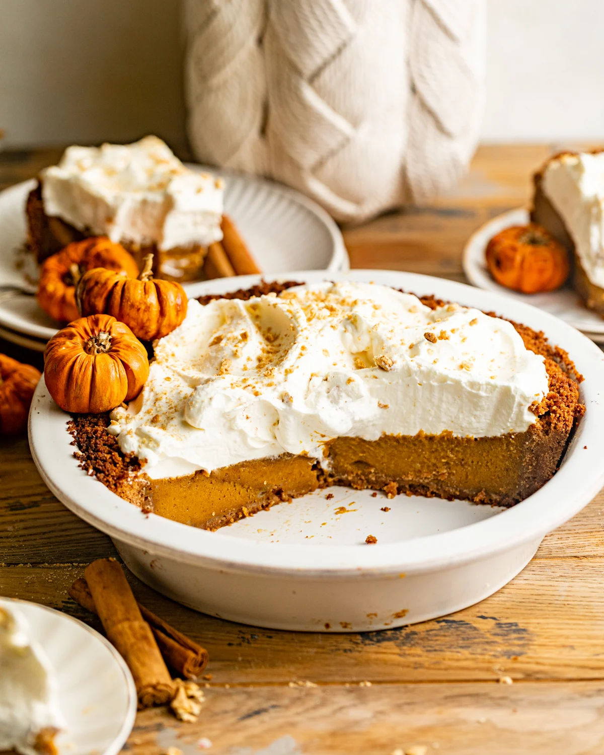 Pumpkin pie in a white baking dish topped with whipped cream.