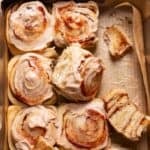 Apple cinnamon rolls in a baking pan with cream cheese icing and apple butter swirled on top.