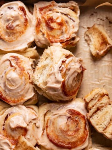 Apple cinnamon rolls in a baking pan with cream cheese icing and apple butter swirled on top.