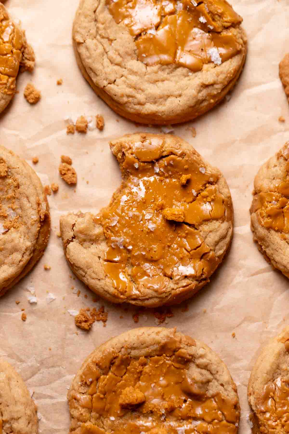 Biscoff butter cookies topped with speculoos and flaky sea salt on parchment paper.