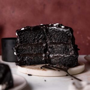 Black velvet cake cut in half on a white marble platter.