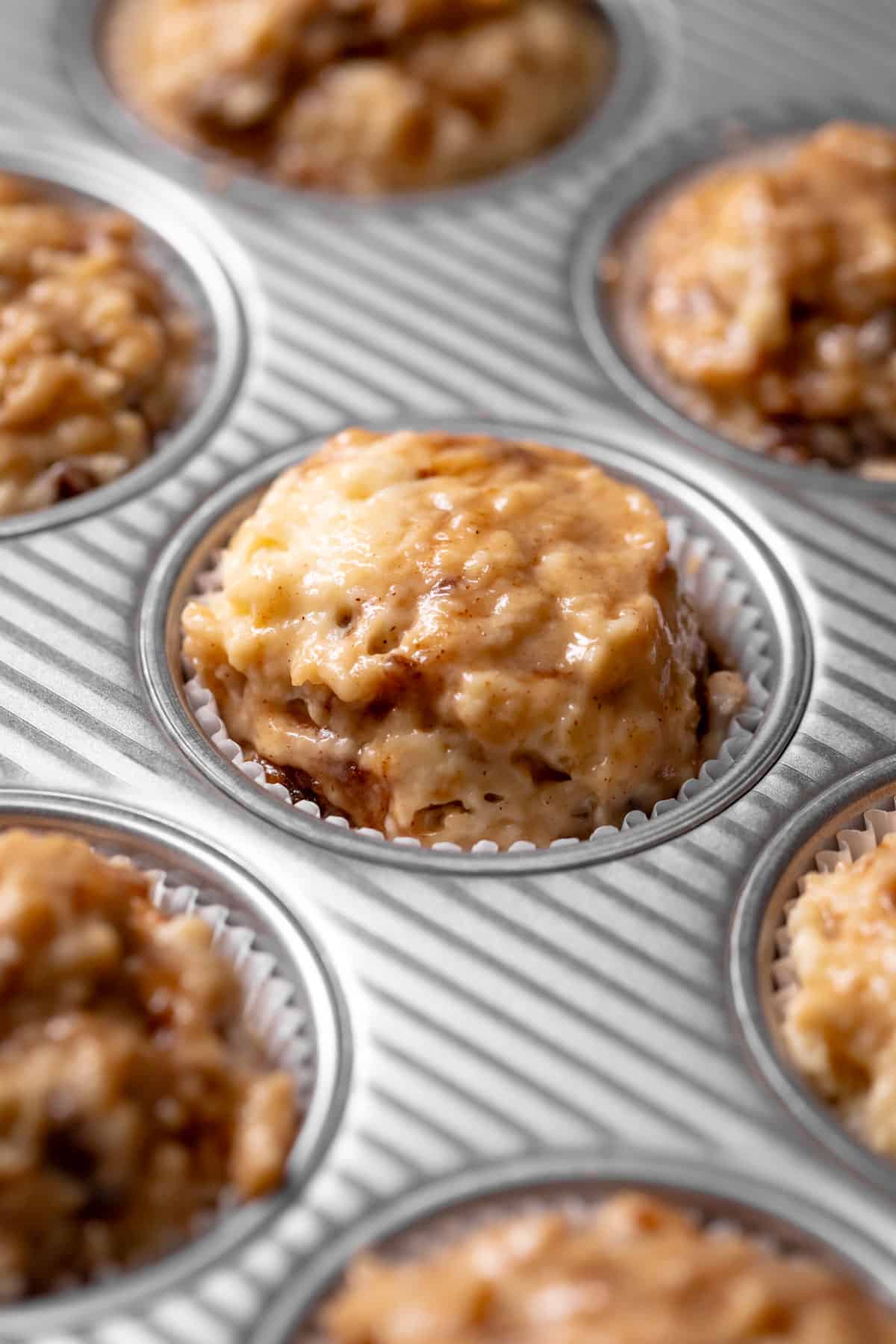 A muffin pan with the cinnamon batter scooped into the muffin liners.