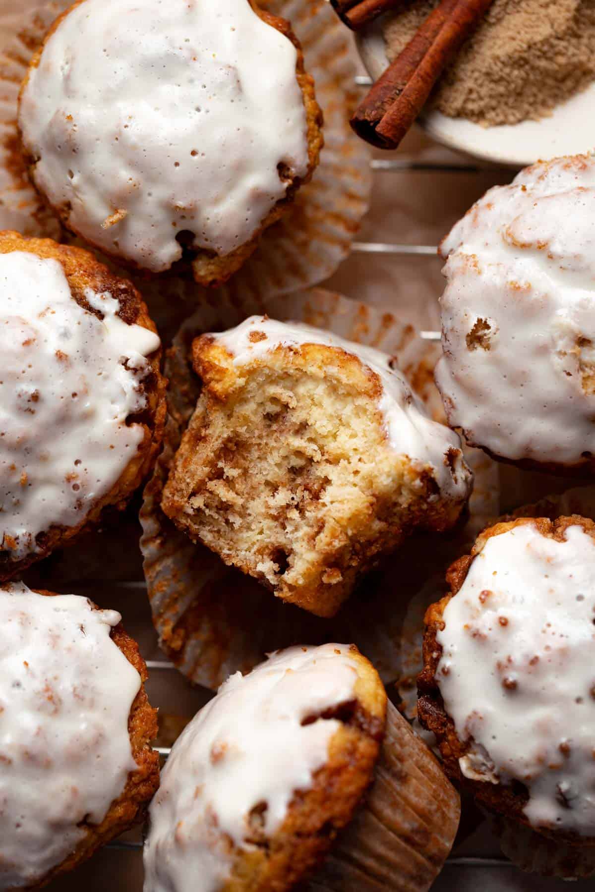 A cinnamon roll muffin with a bite taken out of it to show the cinnamon sugar swirls inside.