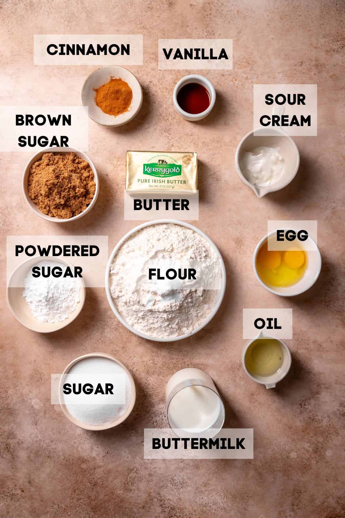 Ingredients needed to make cinnamon muffins in bowls with labels.