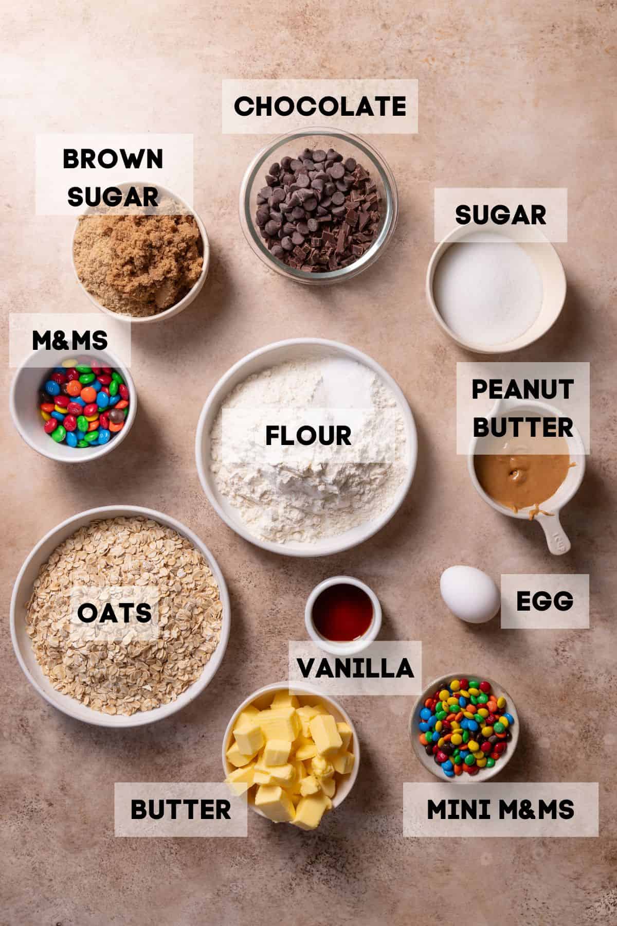 Ingredients for monster cookie bars in bowls with labels.