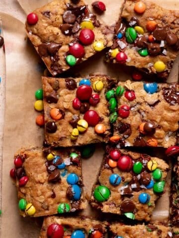 Monster cookie bars on parchment paper with mm candies and chocolate chips on top.