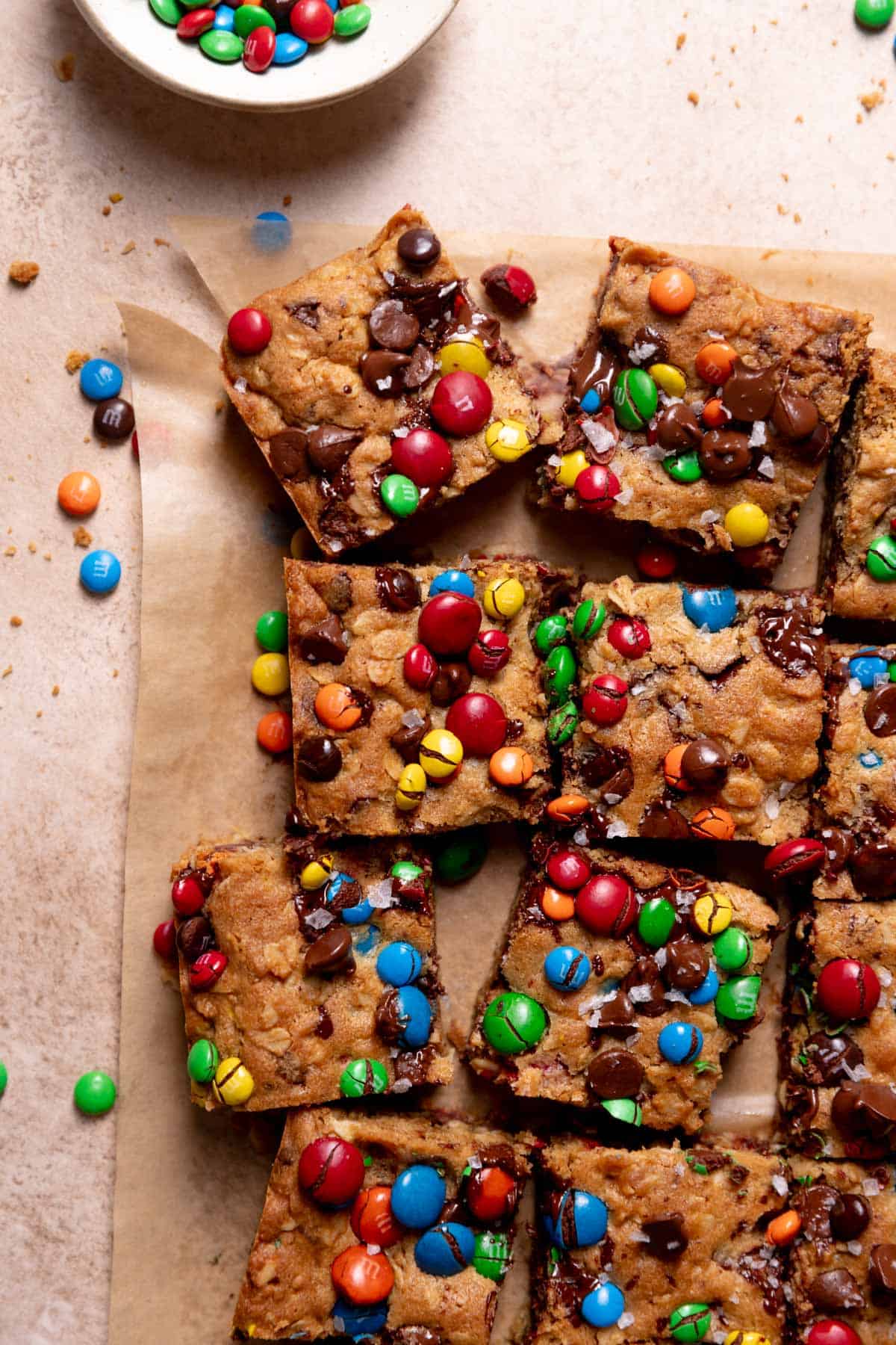 Monster cookie bars on parchment paper surrounded by mm candies.