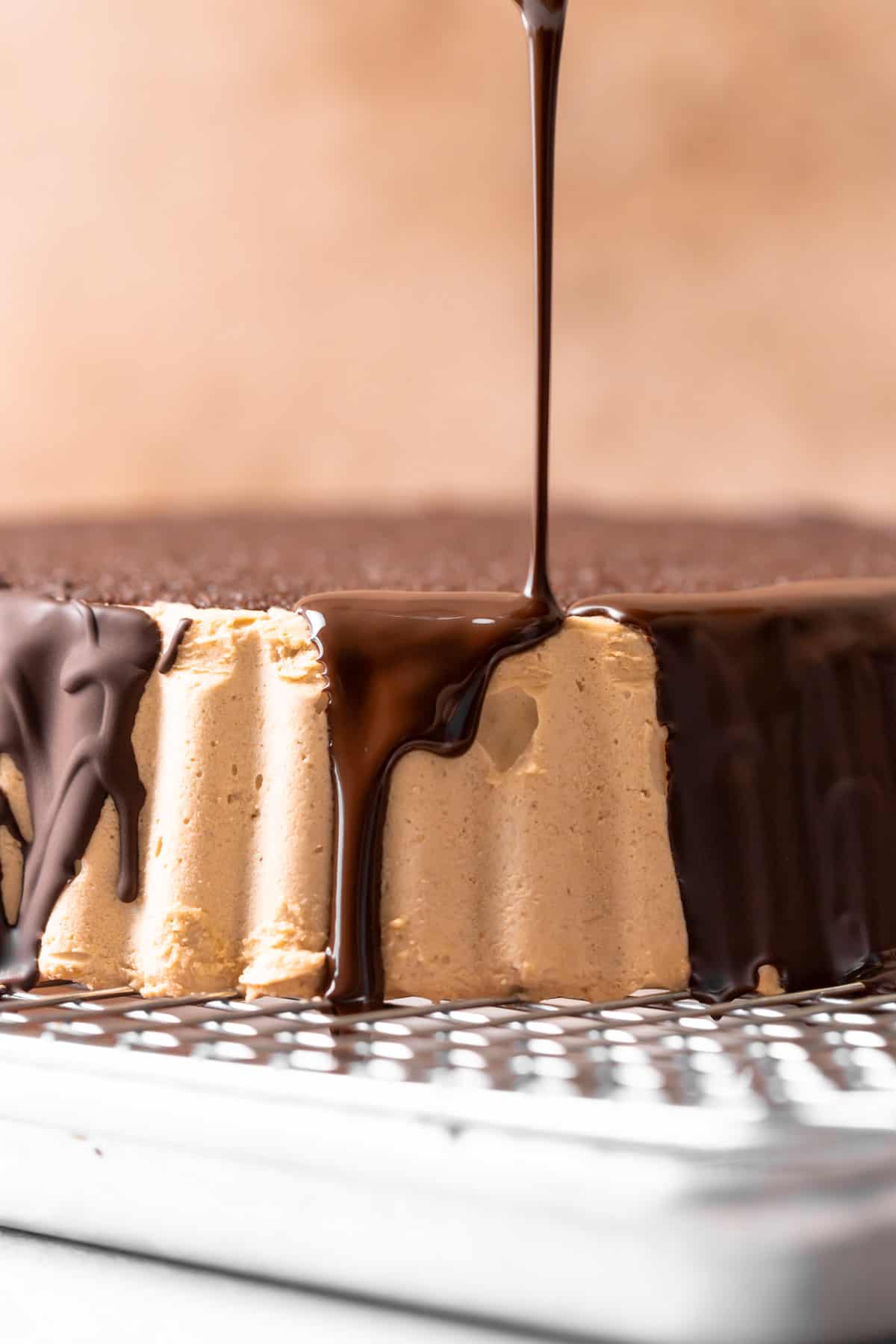A stream of chocolate ganache being poured over the edge of the cake to drip down the sides.