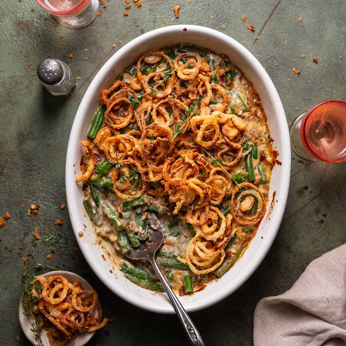 Cheesy green bean casserole in a white baking dish with fried onions on top.