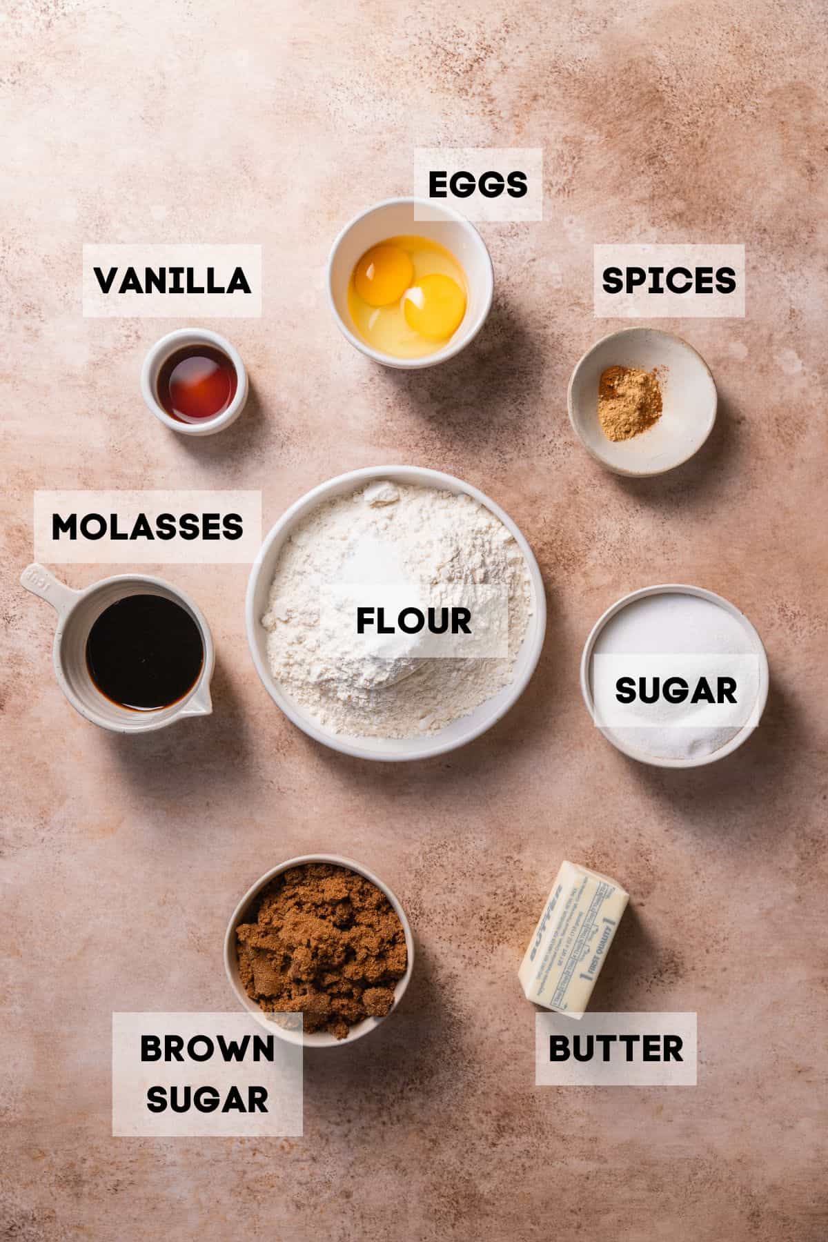 Ingredients needed to make molasses cookies in bowls with labels.