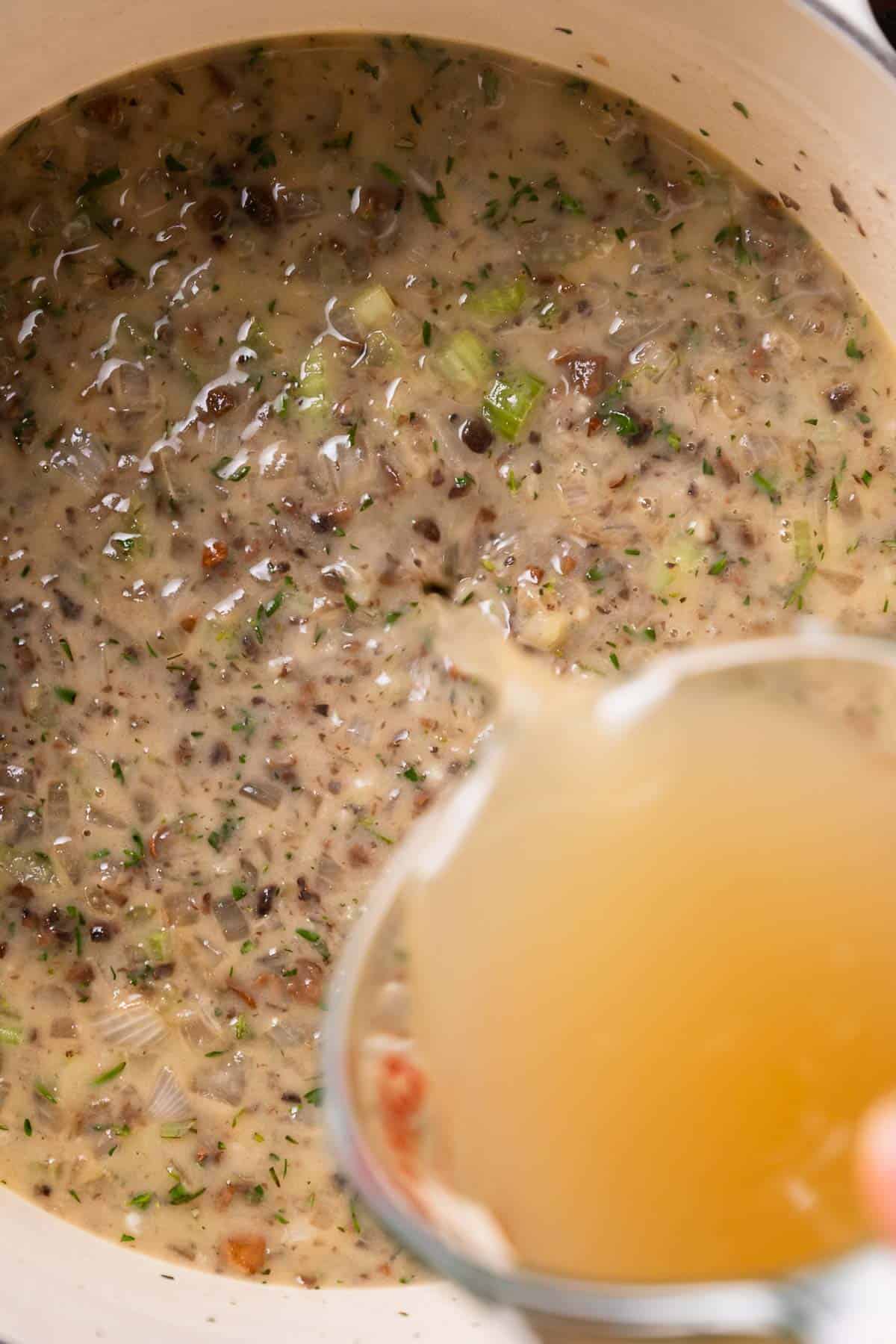 Chicken broth being poured into the sauce.
