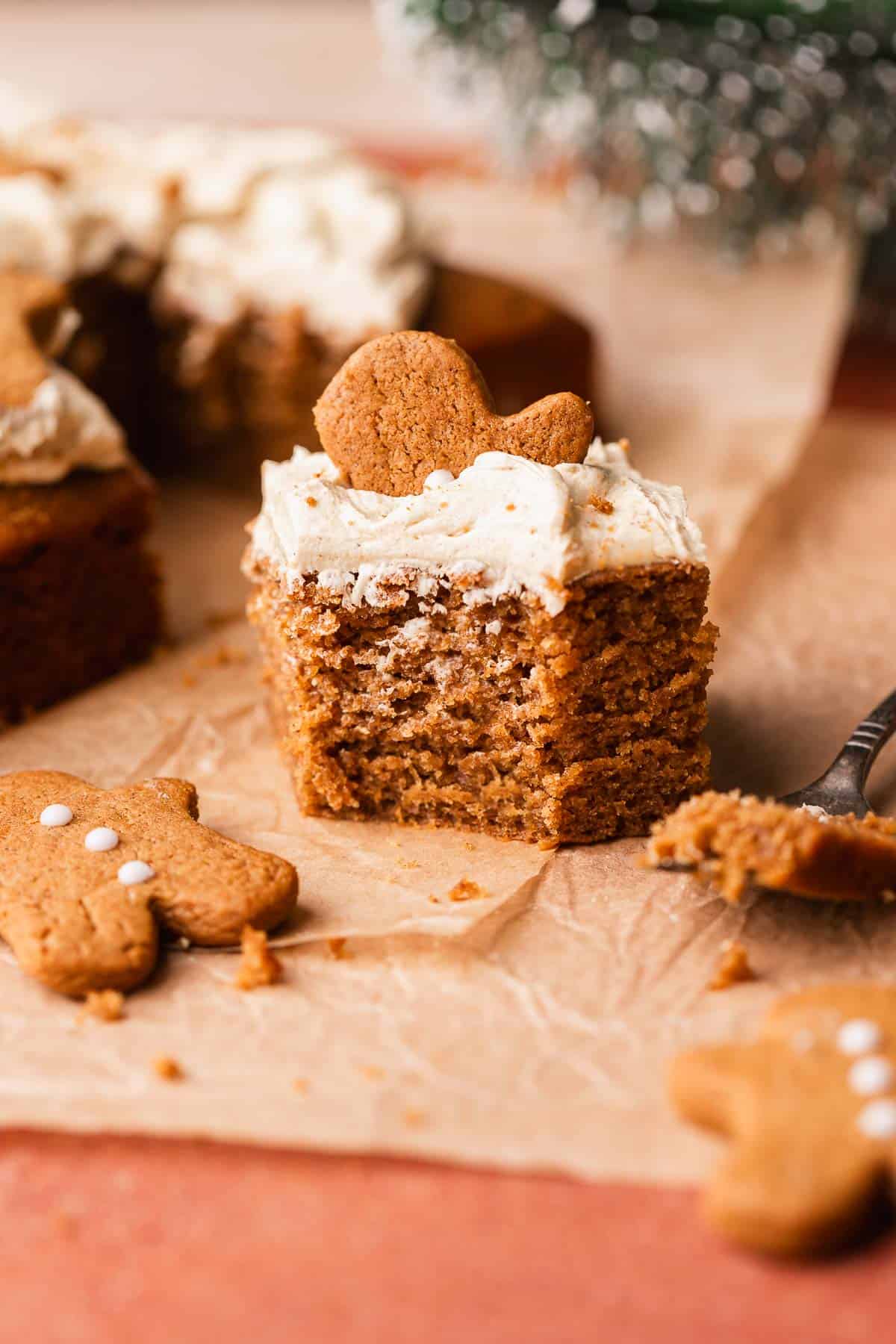 A slice of gingerbread cake with a bite taken out of it on brown parchment paper.