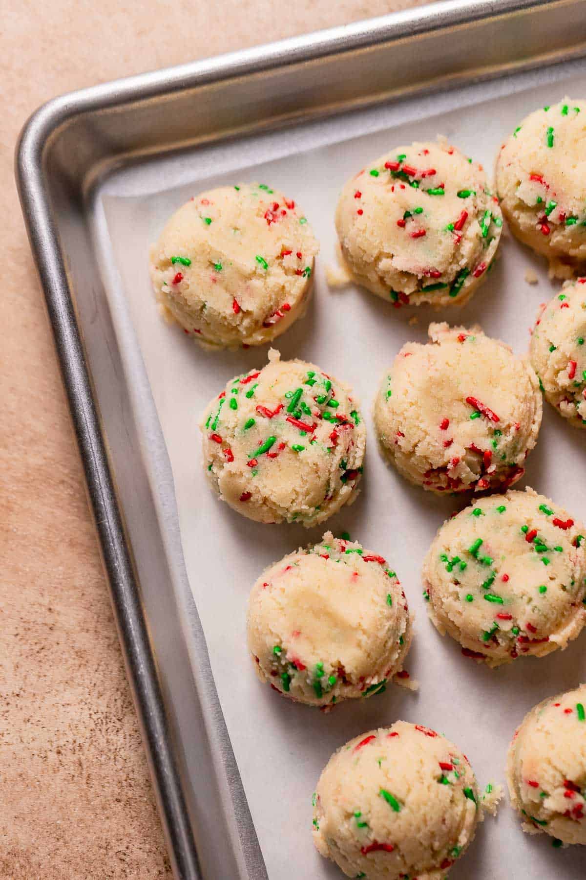 A baking sheet with sugar cookie dough balls.