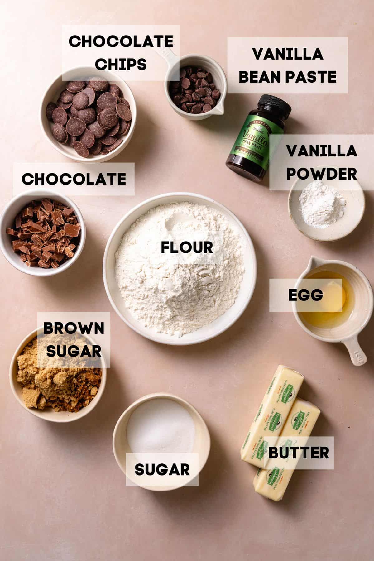 Ingredients needed to make chocolate chip cookies in bowls with labels.