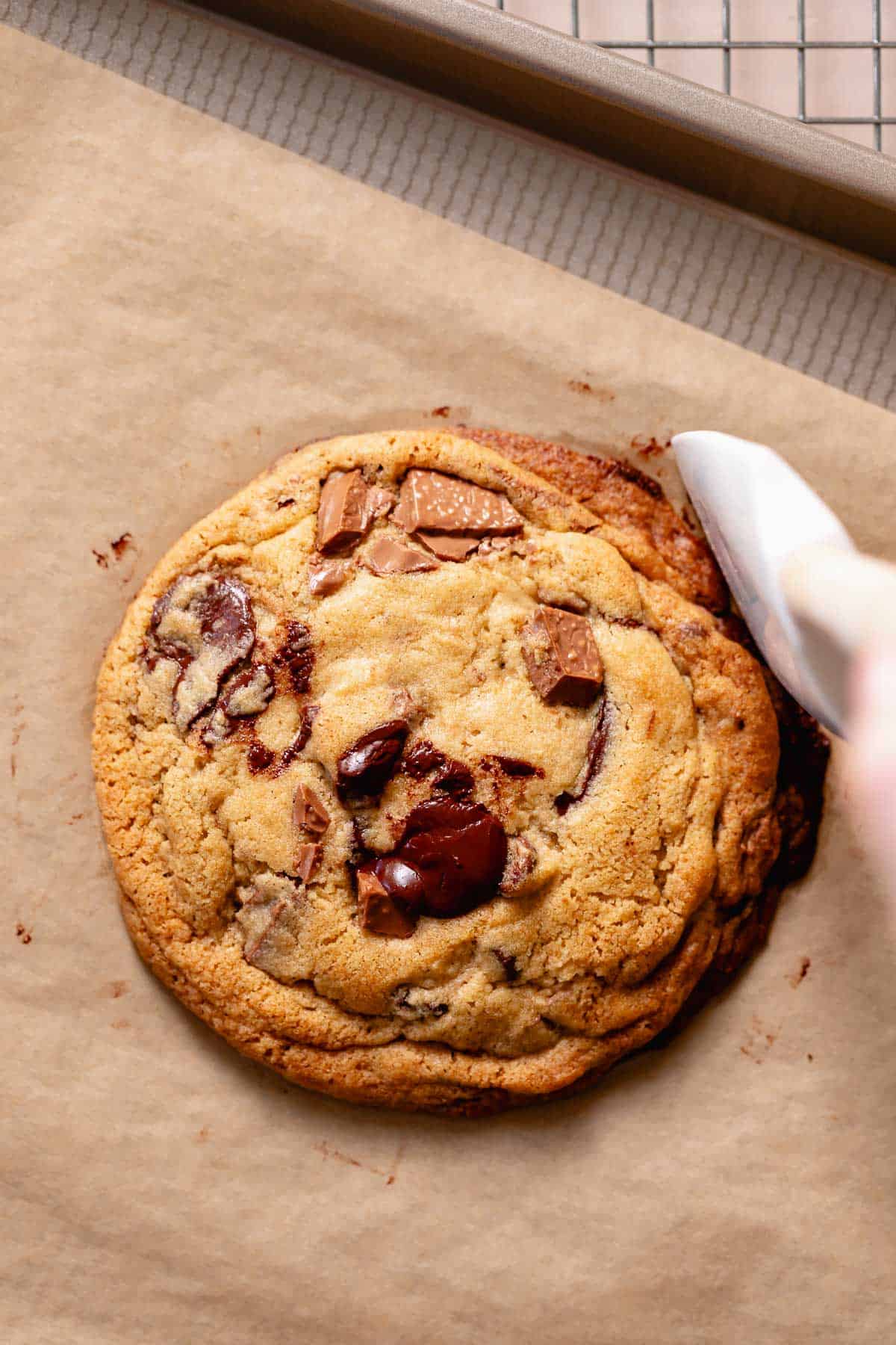 A spatula scooting in the edges of a cookie after baking to make it perfectly round.