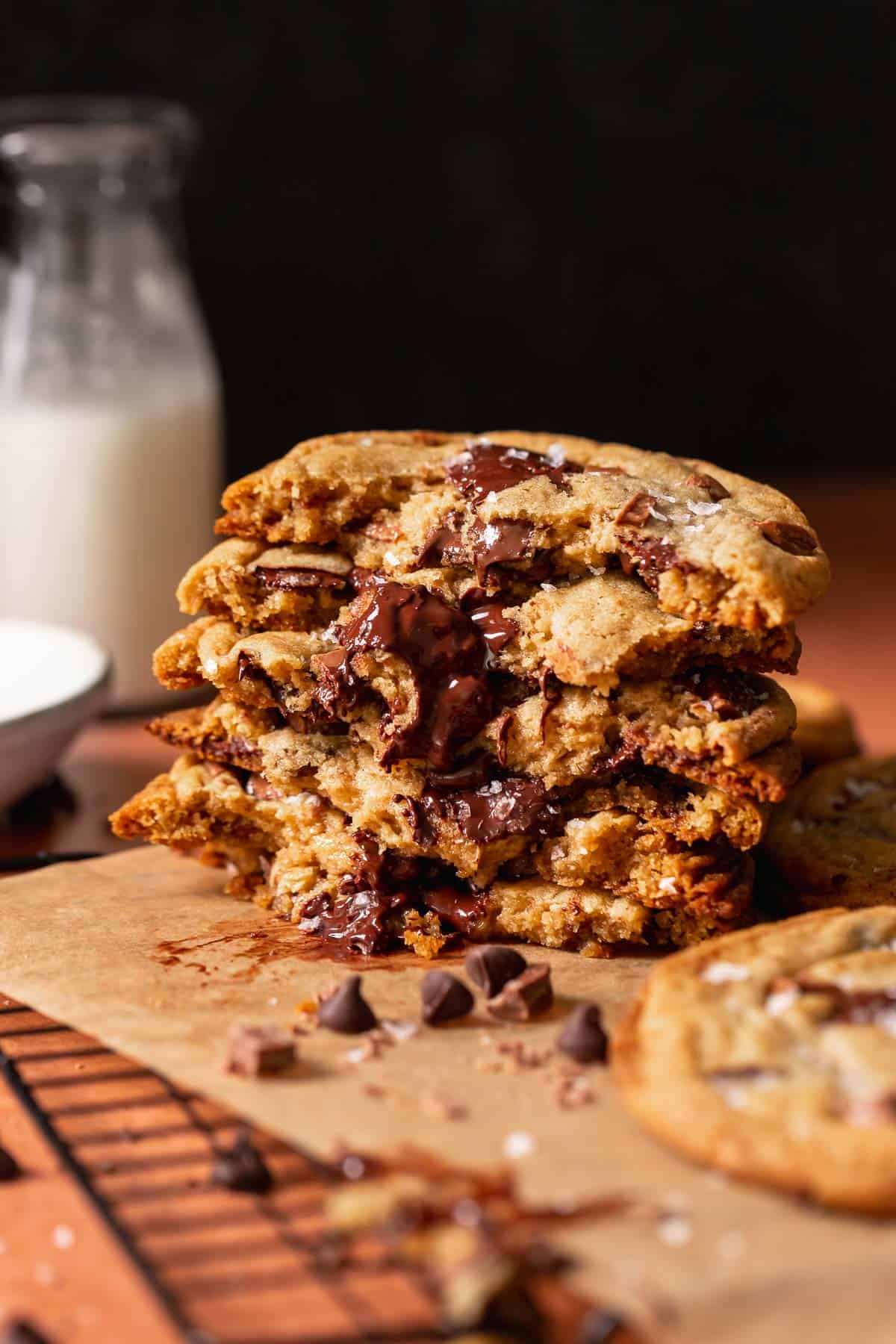 A stack of bakery style chocolate chip cookies that are cut in half to show the gooey centers.