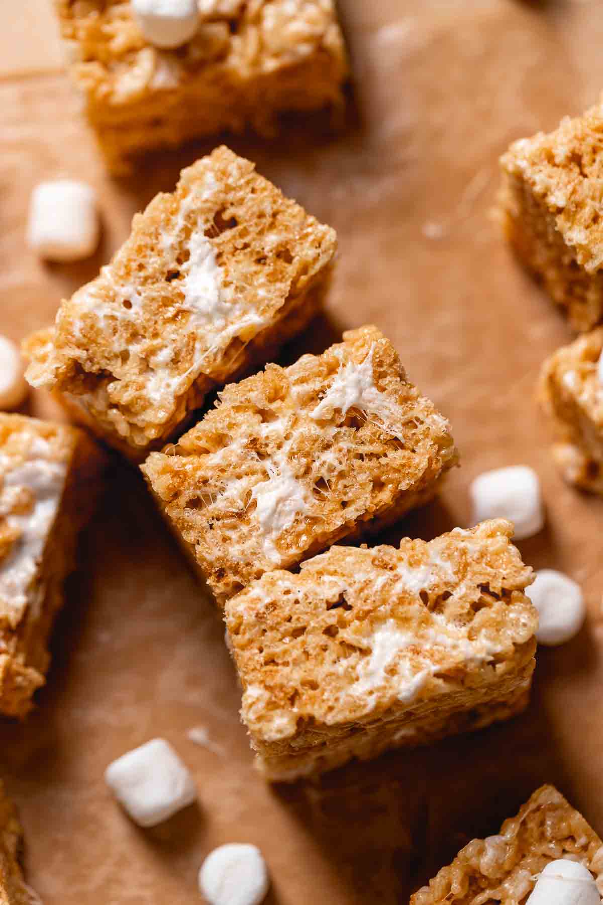 Three rice krispie squares on their sides on parchment paper to show the gooey marshmallow texture.