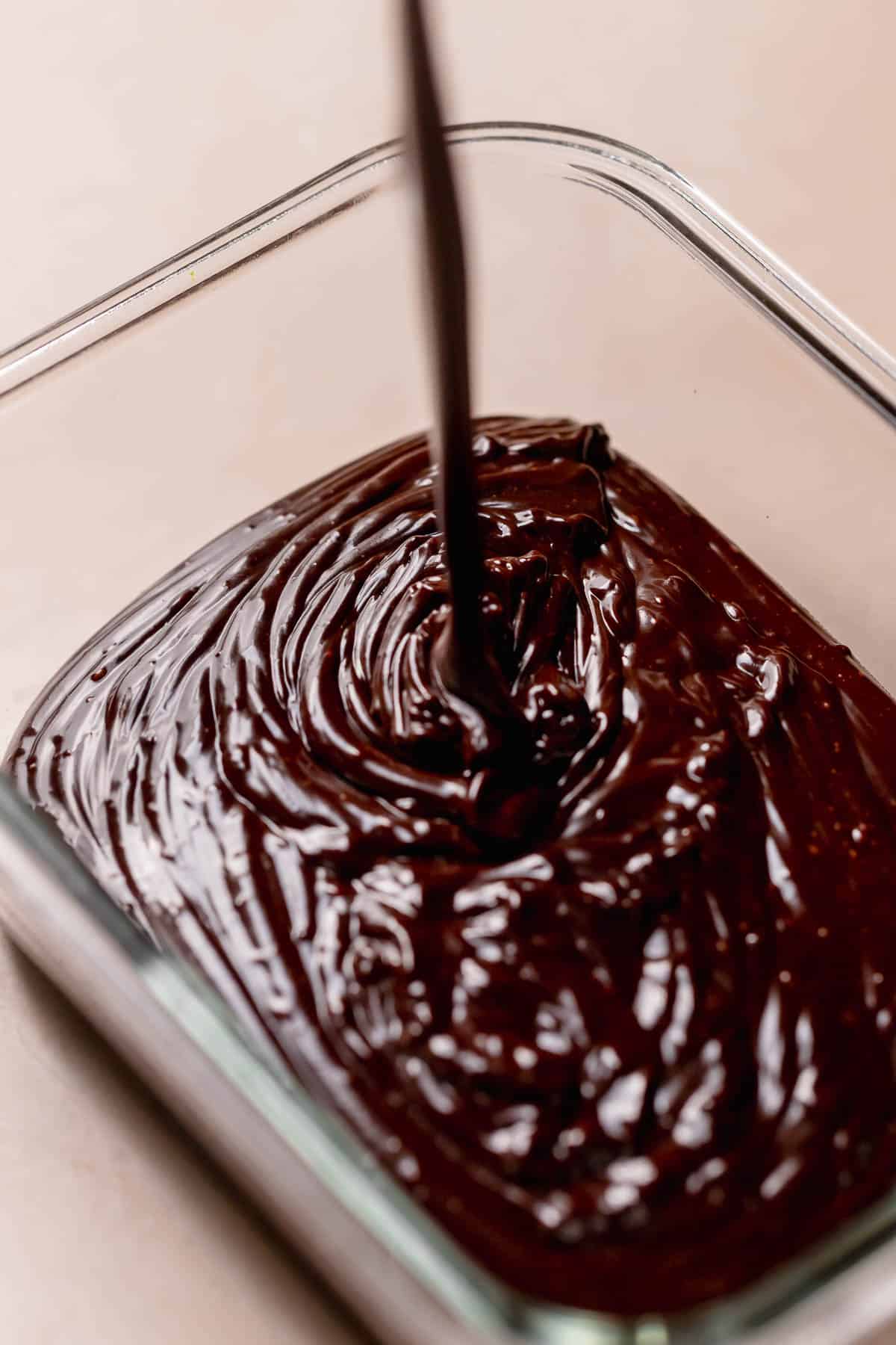 The chocolate fudge icing being poured into a container to set overnight.