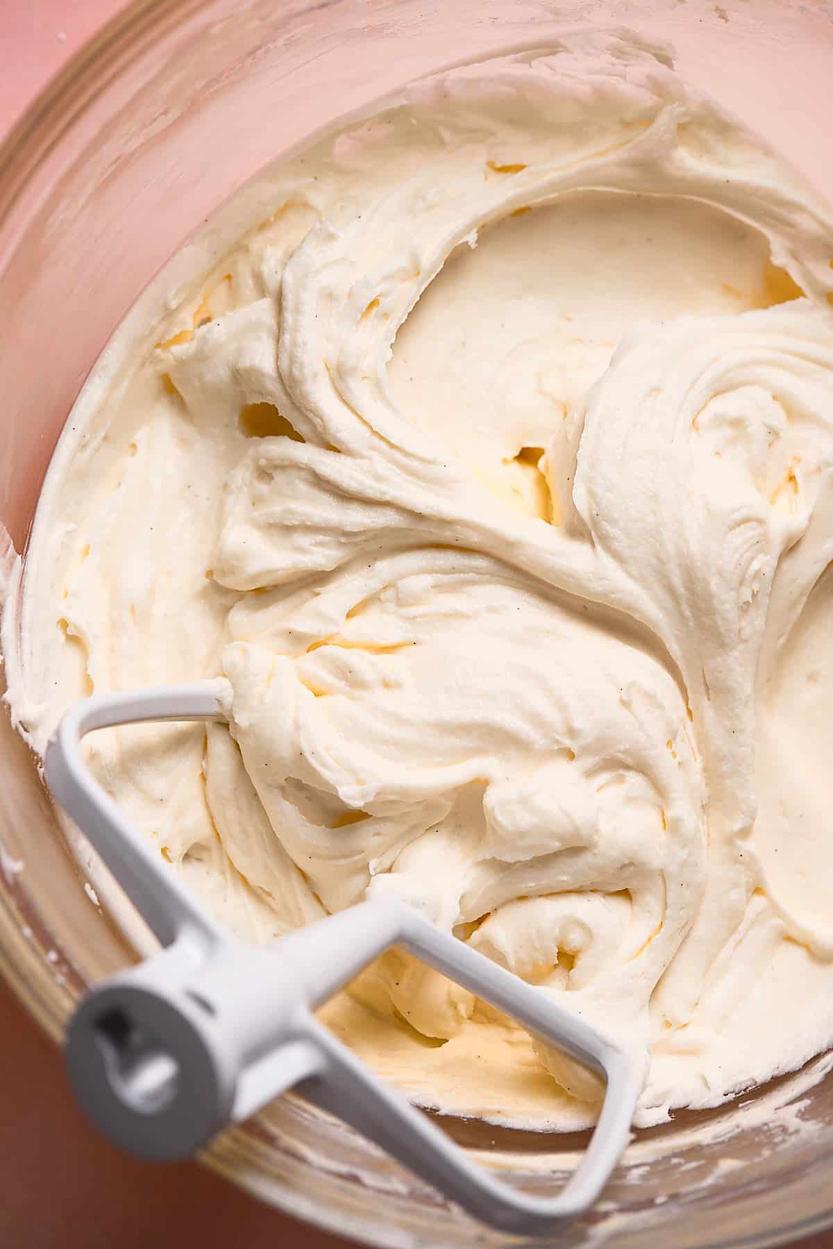 A glass mixing bowl with cream cheese frosting.