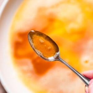 A spoon holding liquid browned butter over a pan.