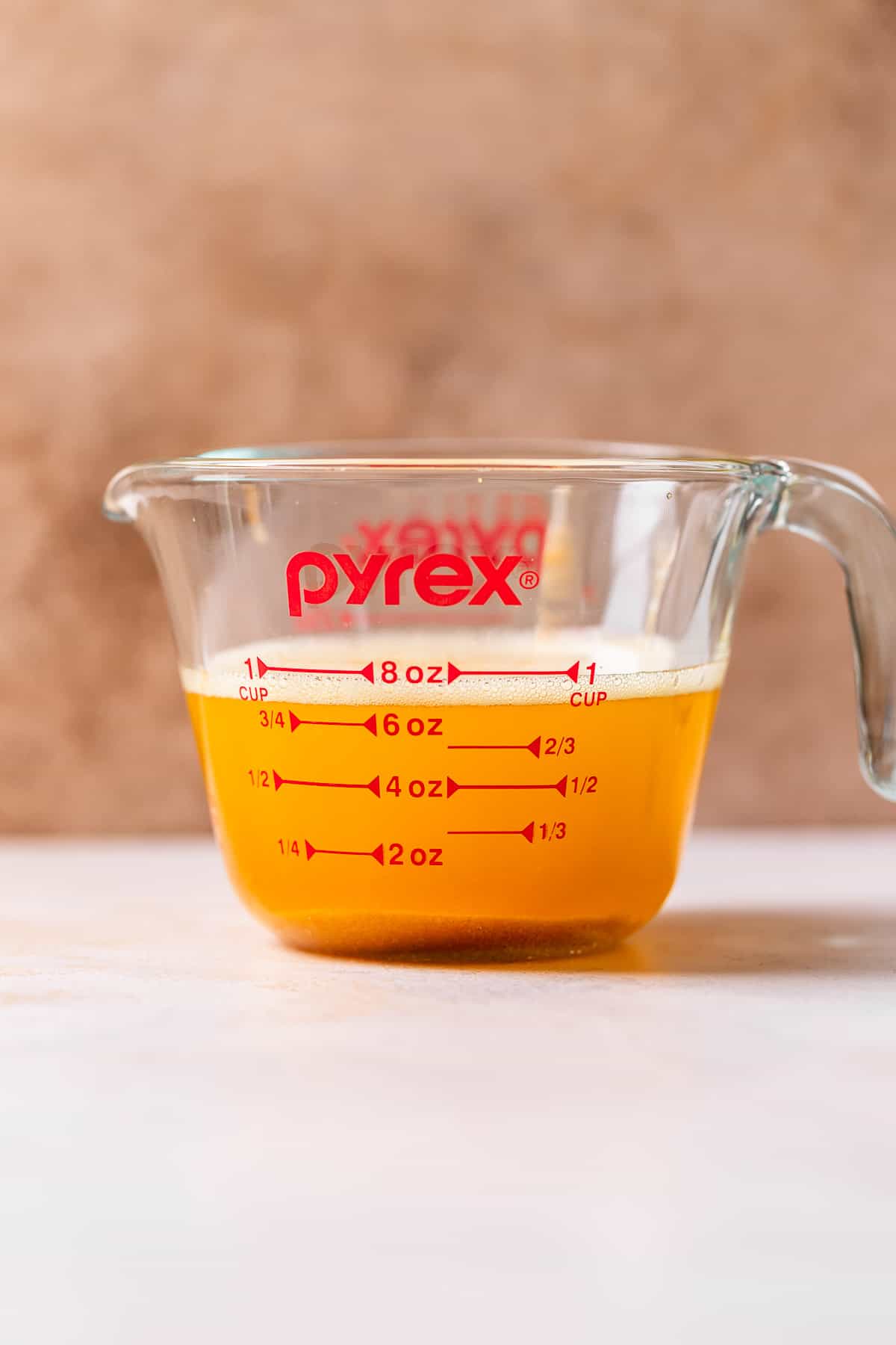 A glass pyrex measuring cup with browned european butter to show the moisture loss after browning.