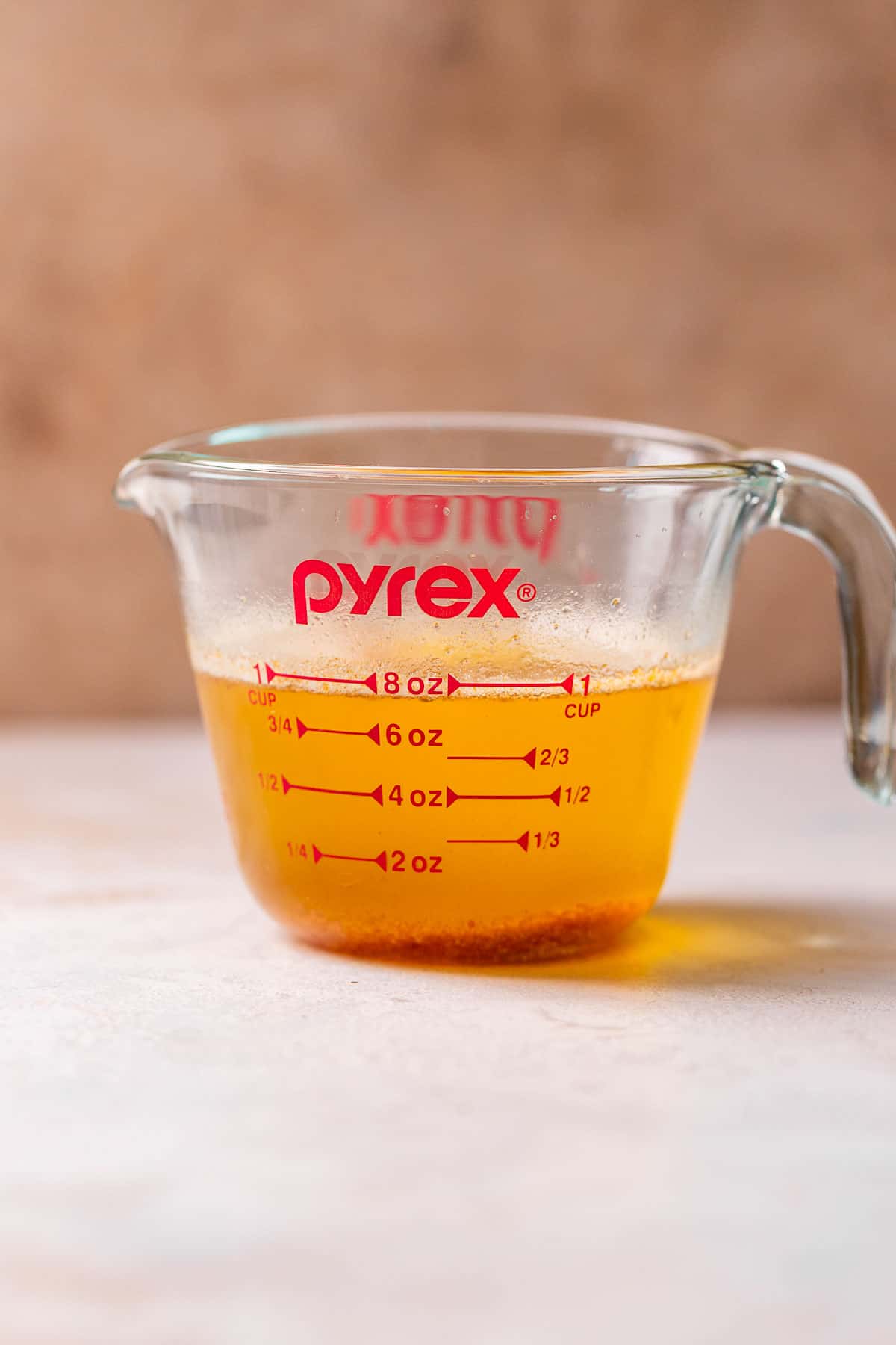 A glass pyrex measuring cup with browned american butter to show the moisture loss after browning.