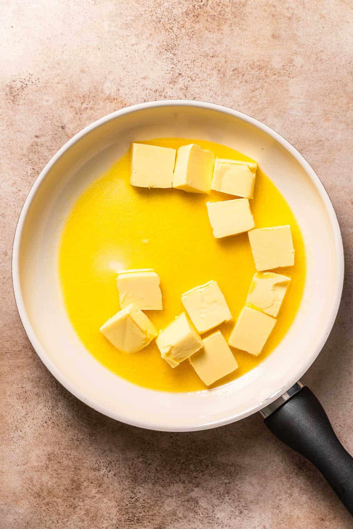 A white pan with butter slices half melted.