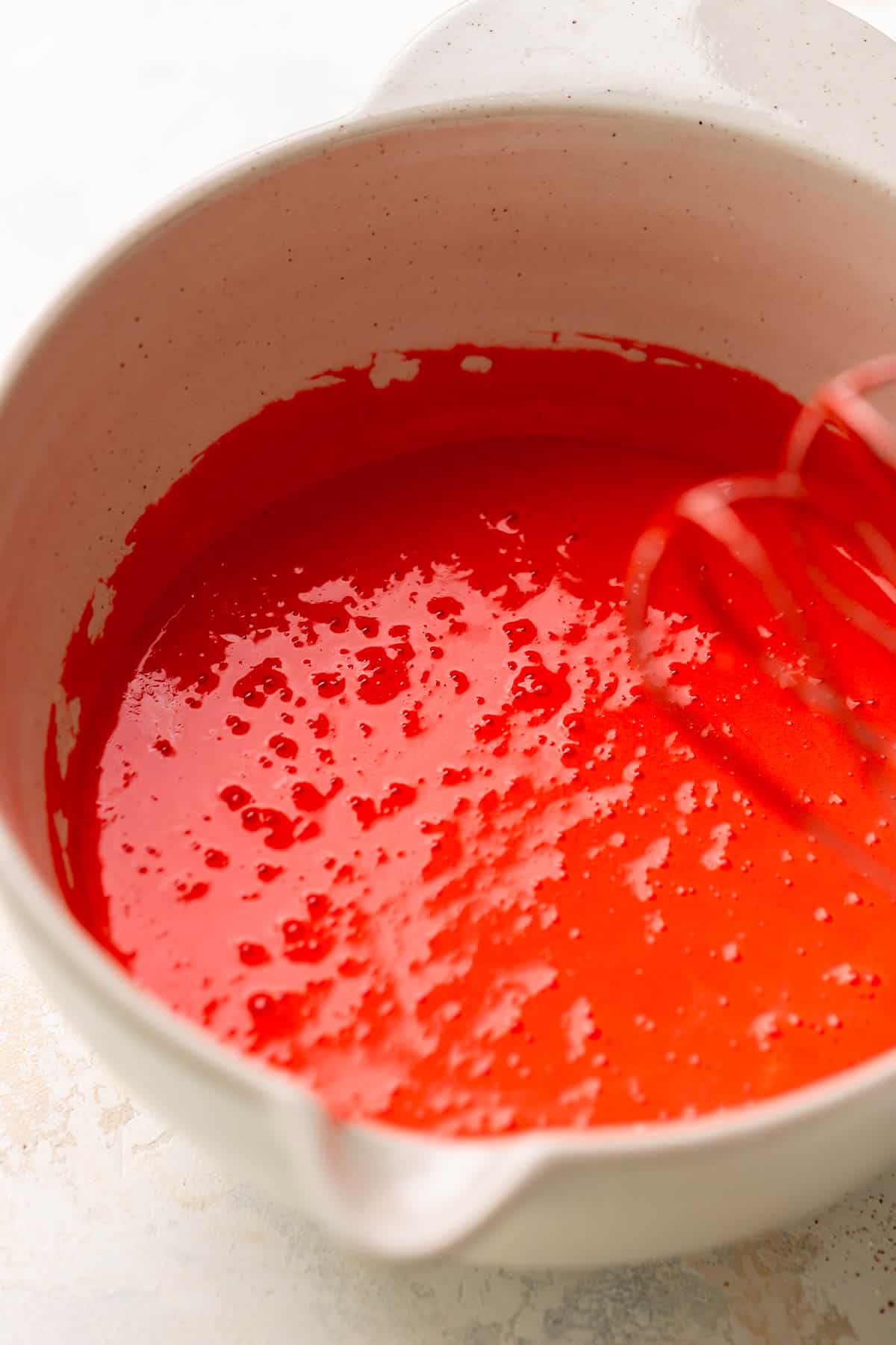 A mixing bowl with the bright red brownie batter after mixing.