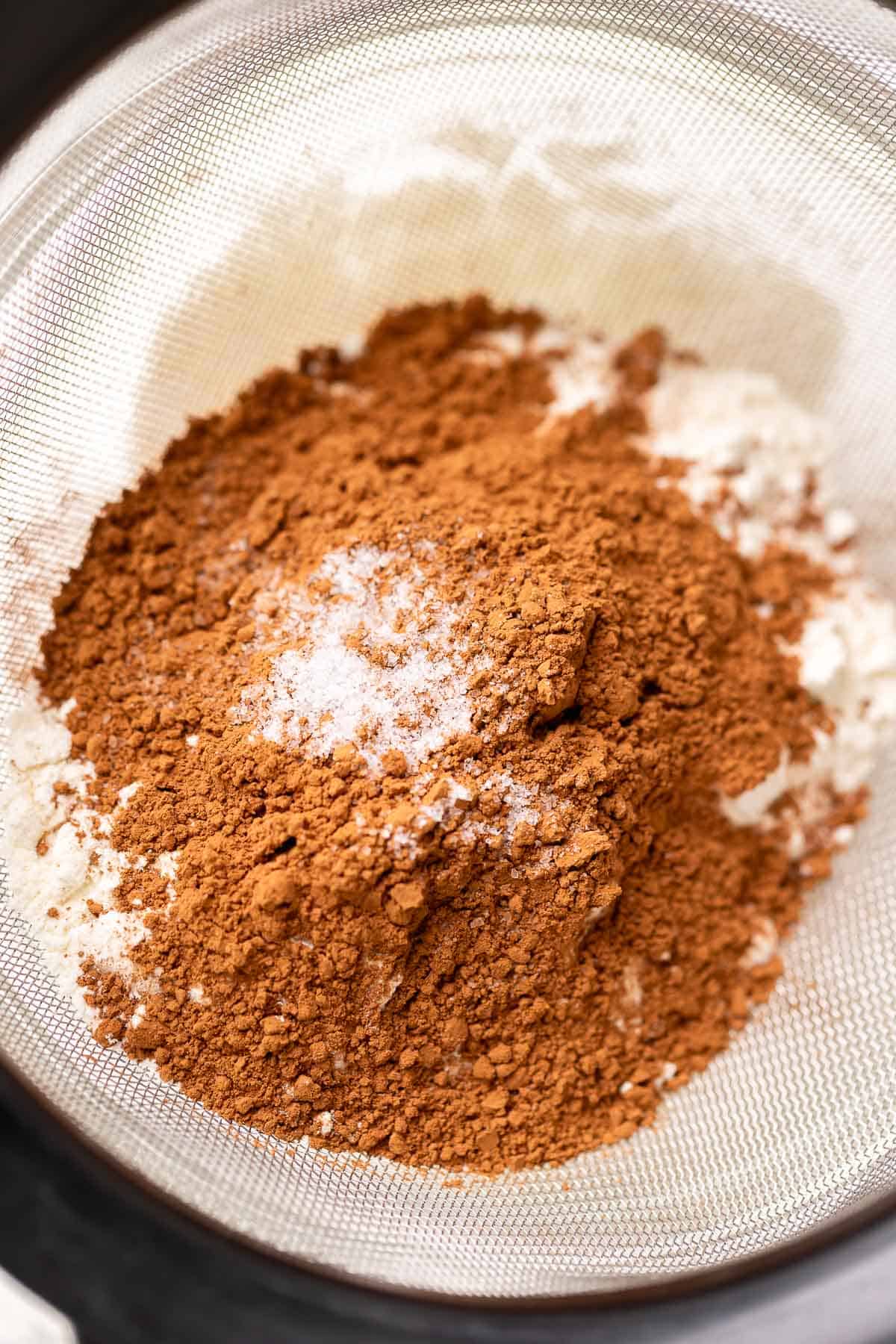 A pile of cocoa powder and flour in a sifter before sifting.