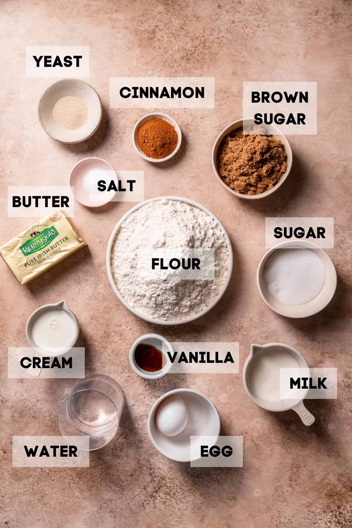 Ingredients needed to make cinnamon buns in bowls with labels.