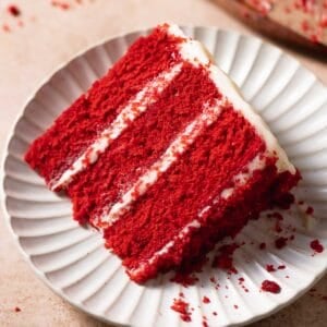 A slice of moist red velvet cake on a white plate.
