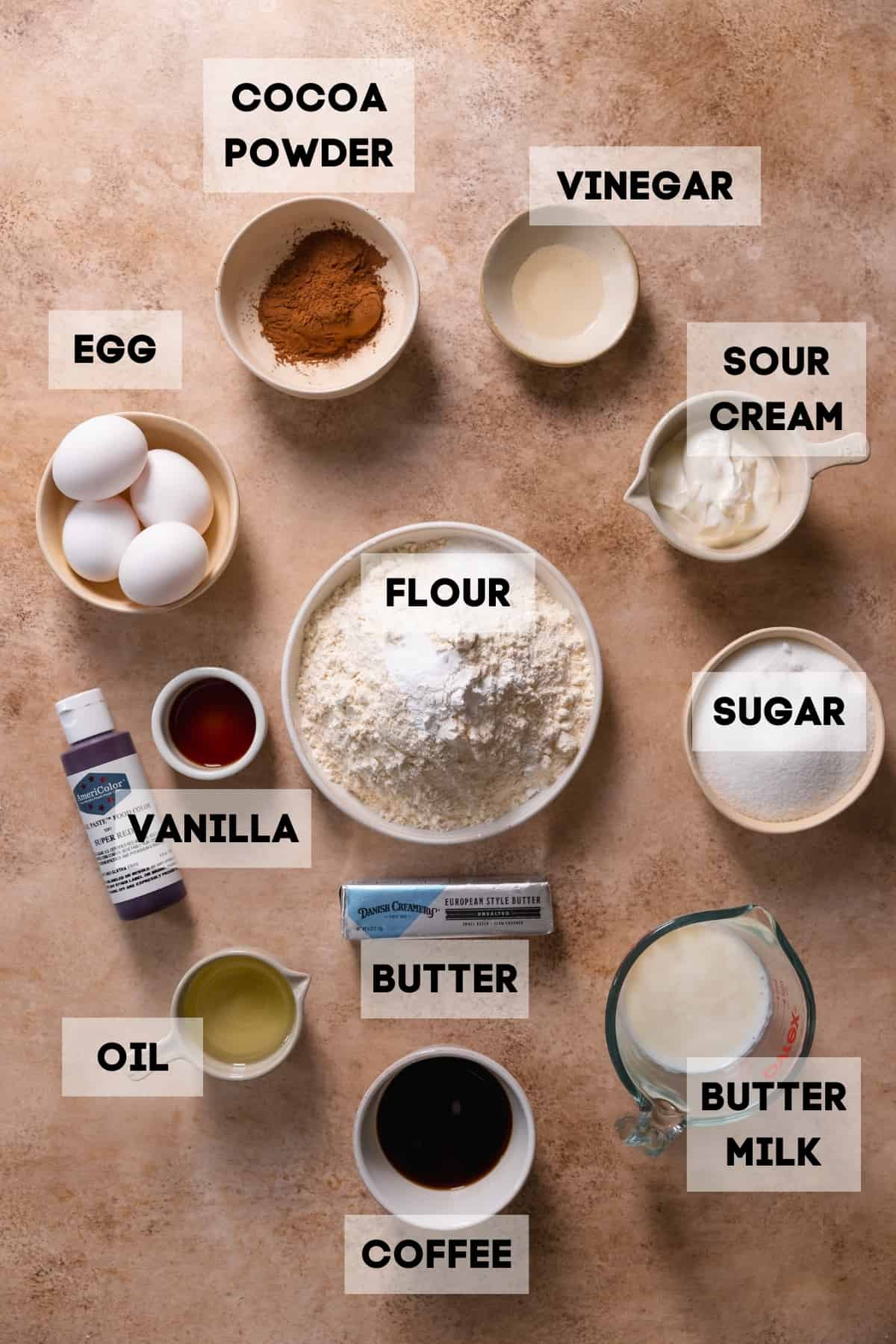 Ingredients needed to make homemade red velvet cake in bowls with labels.