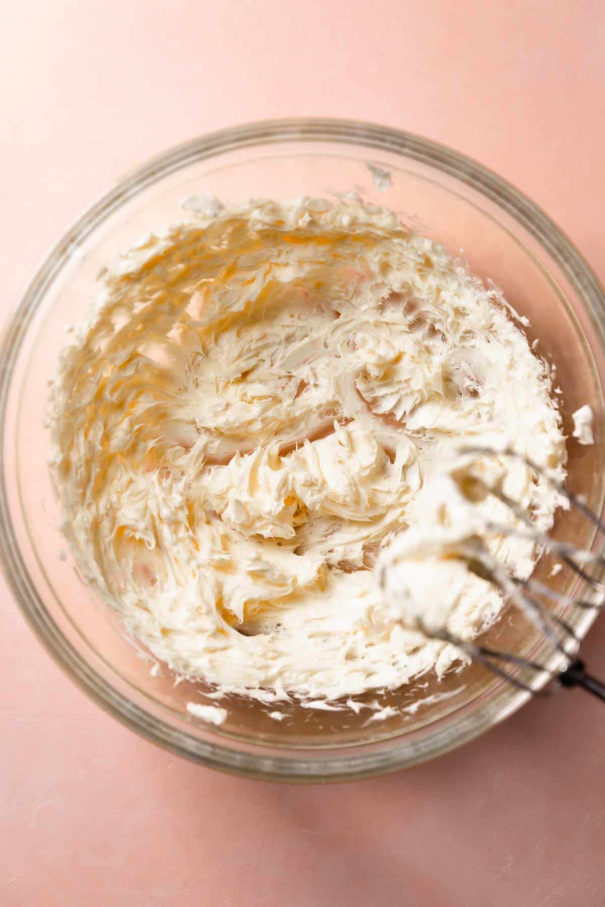 A glass mixing bowl with the creamed butters and cream cheese.