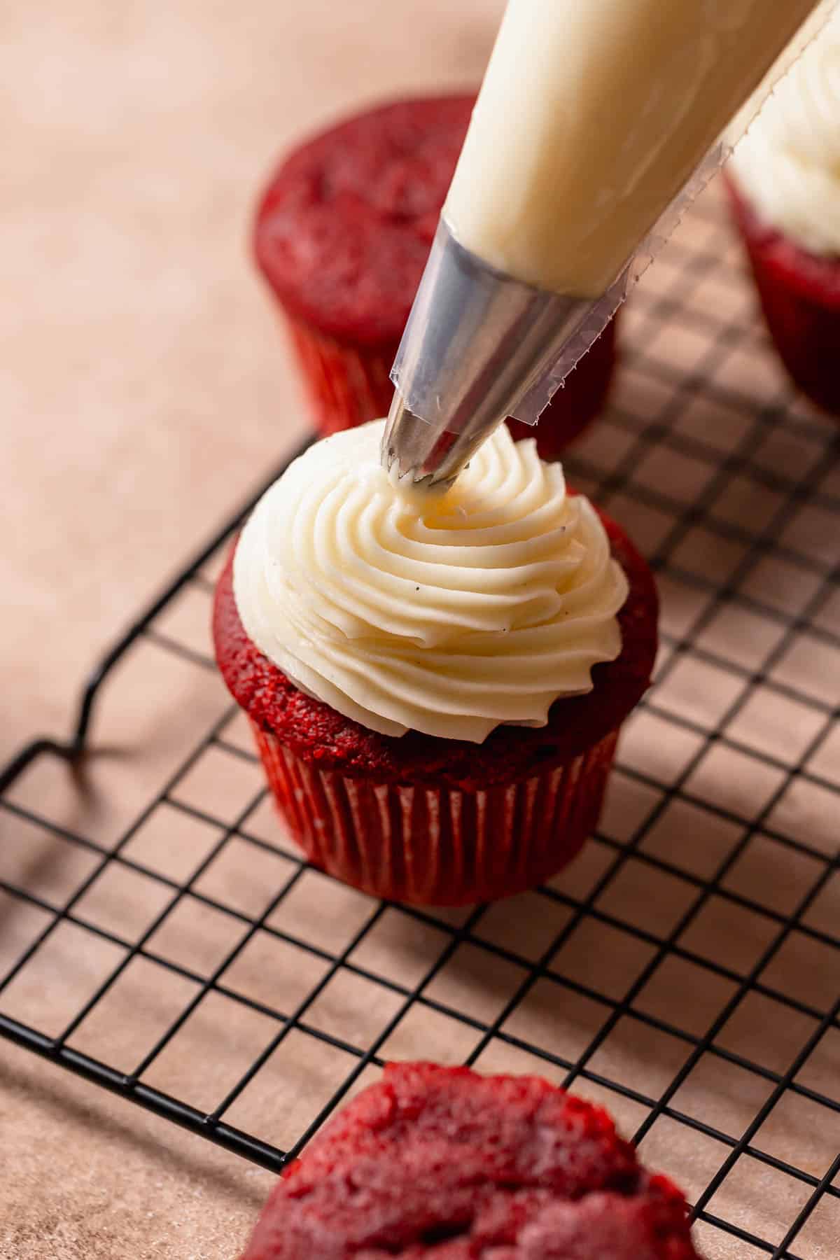 Cream cheese buttercream frosting being piped on top of a cupcake.