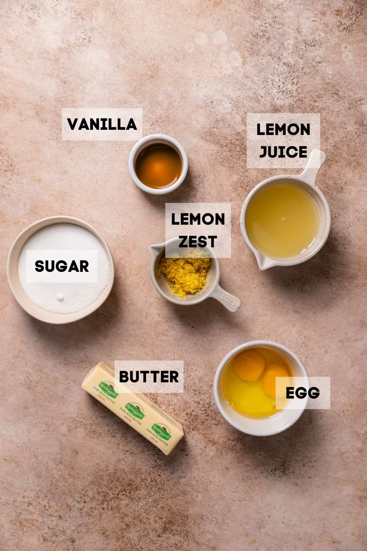 Ingredients needed to make lemon curd from scratch in bowls with labels.