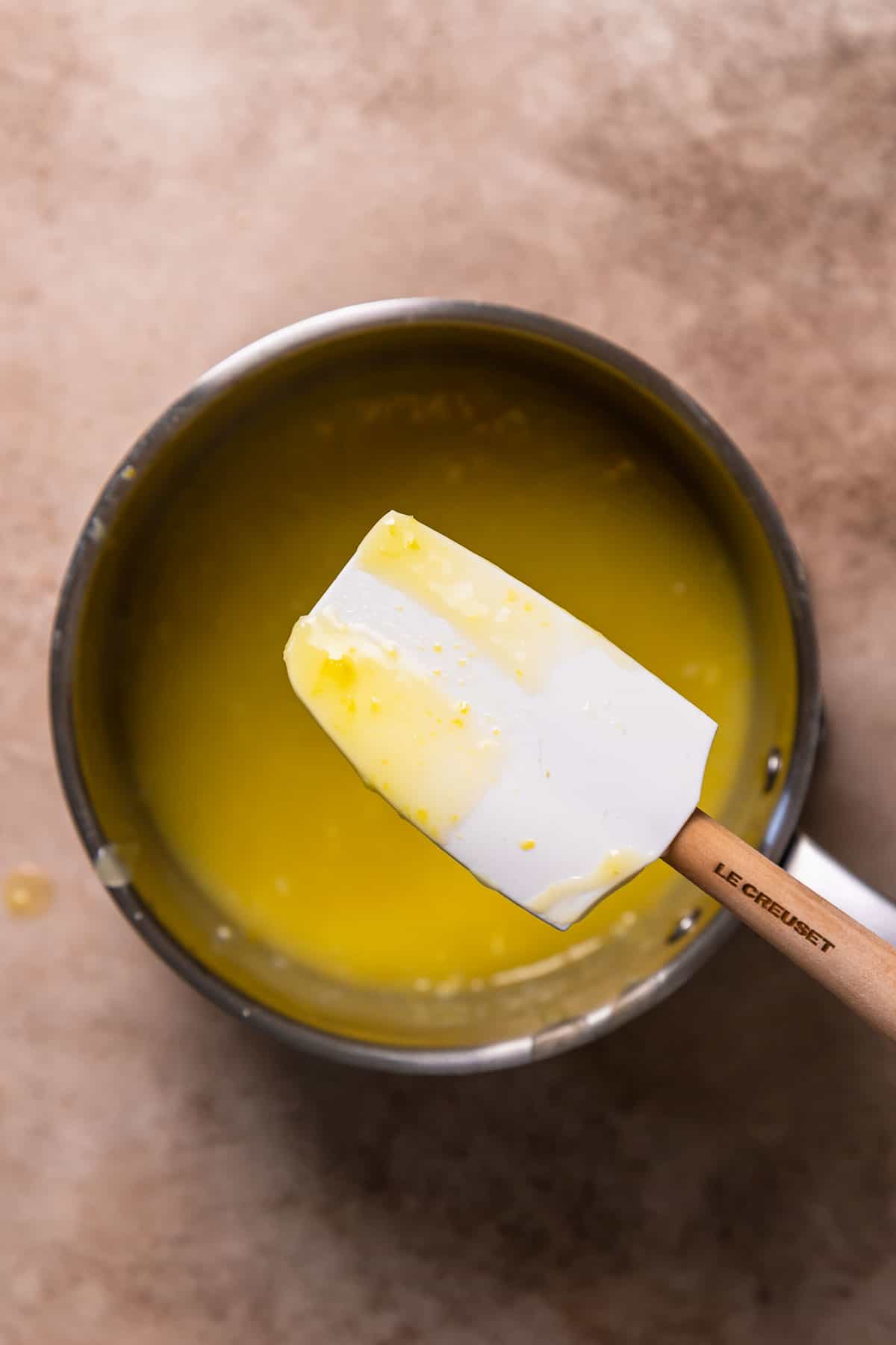 A spatula coated in lemon curd to show the thickened texture.