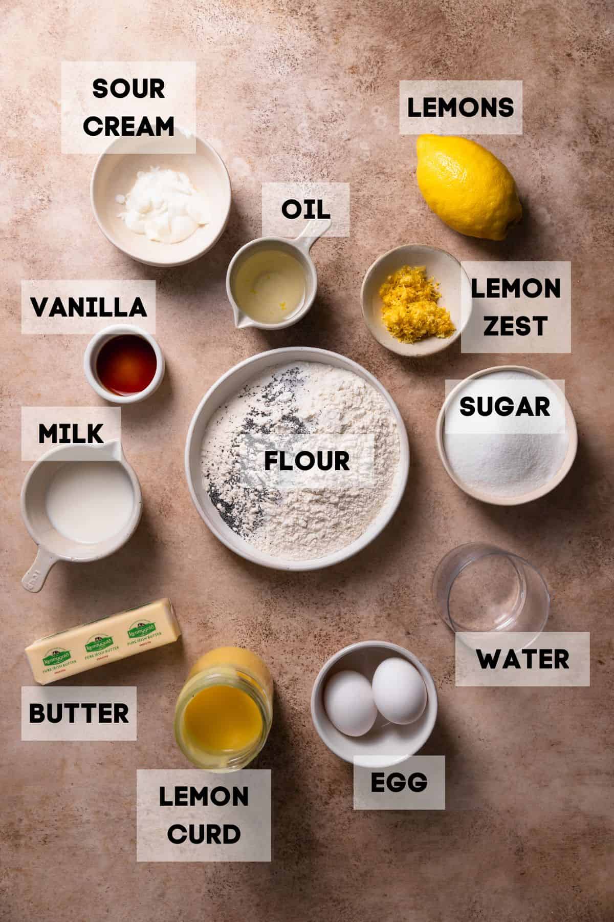 Ingredients needed to make lemon poppy seed cake in bowls with labels.